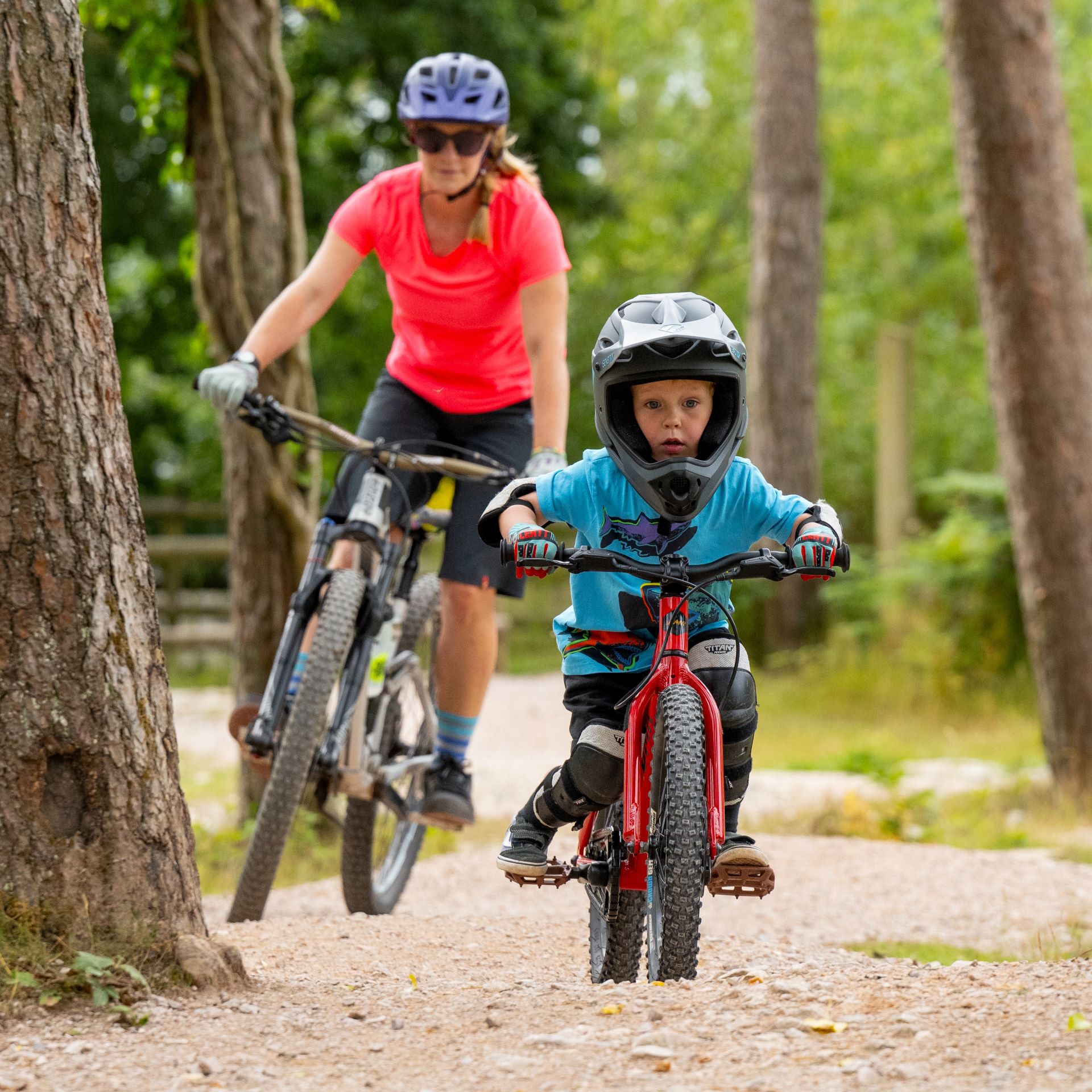 A woman and her son cycle through the forest