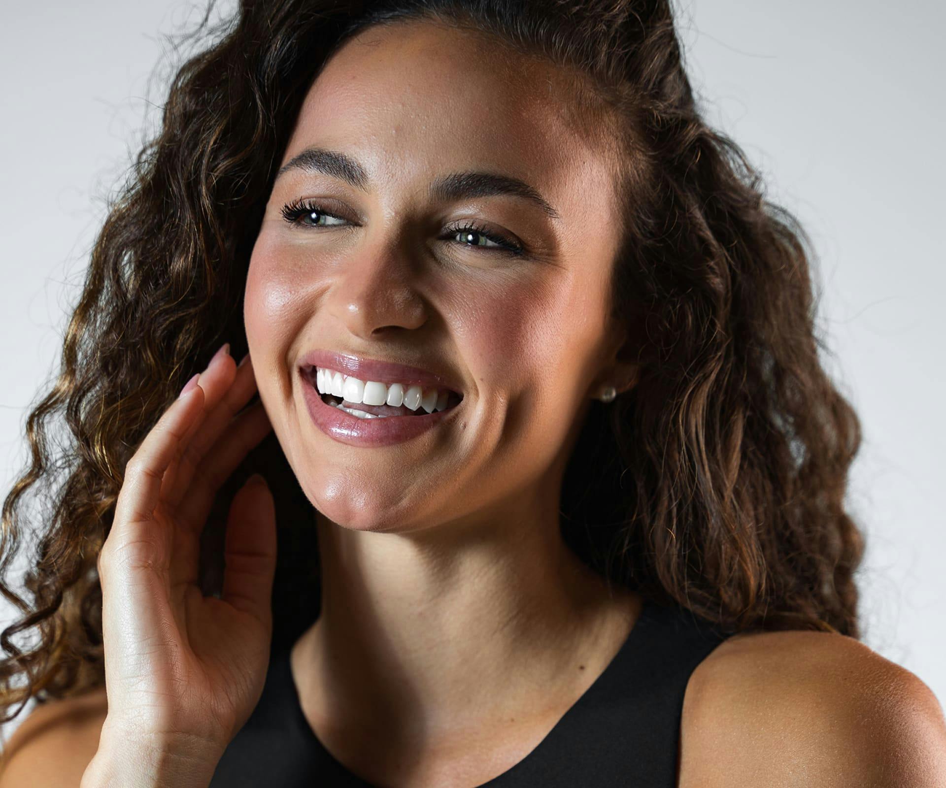 Woman smiling touching her cheek