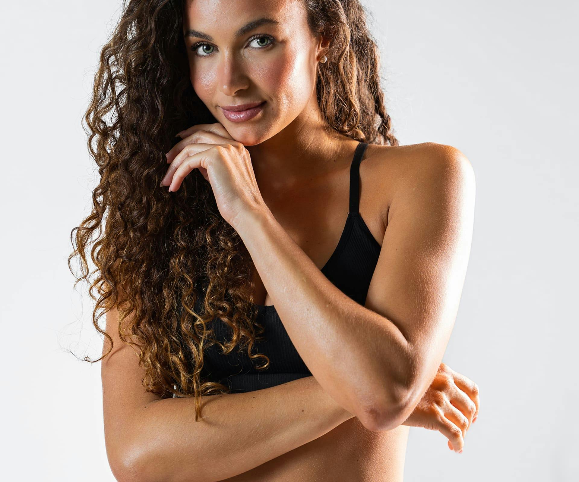 woman with curly hair with her hand near her chin