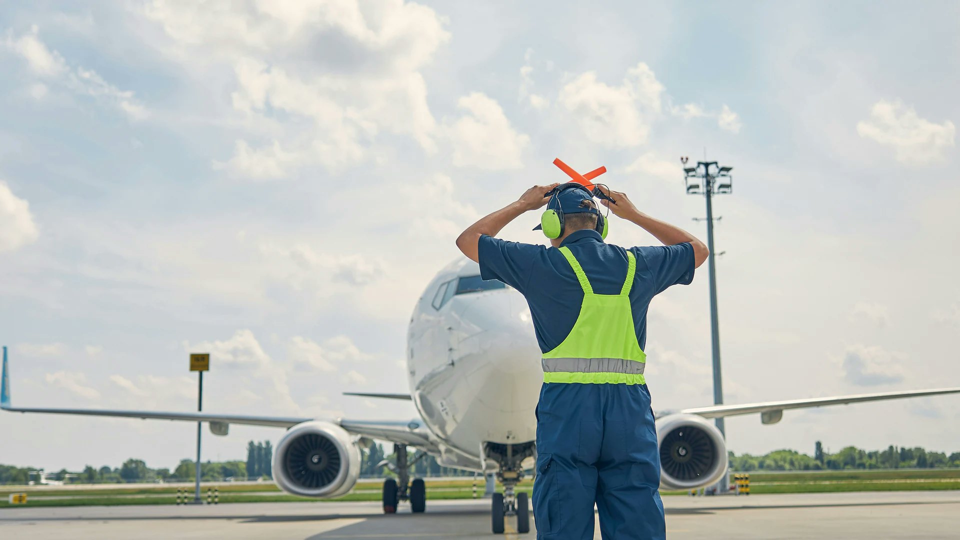 Agent de trafic aérien au sol devant un avion