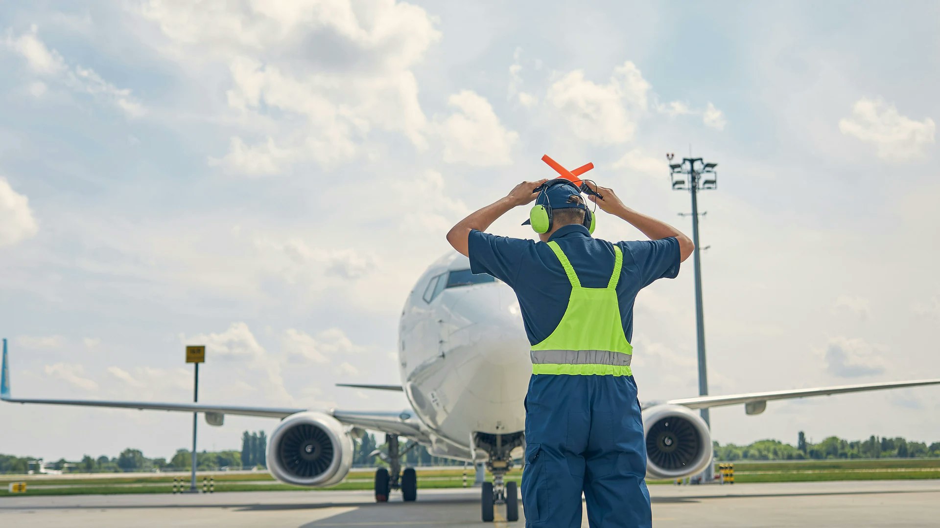 Agent de trafic aérien au sol devant un avion