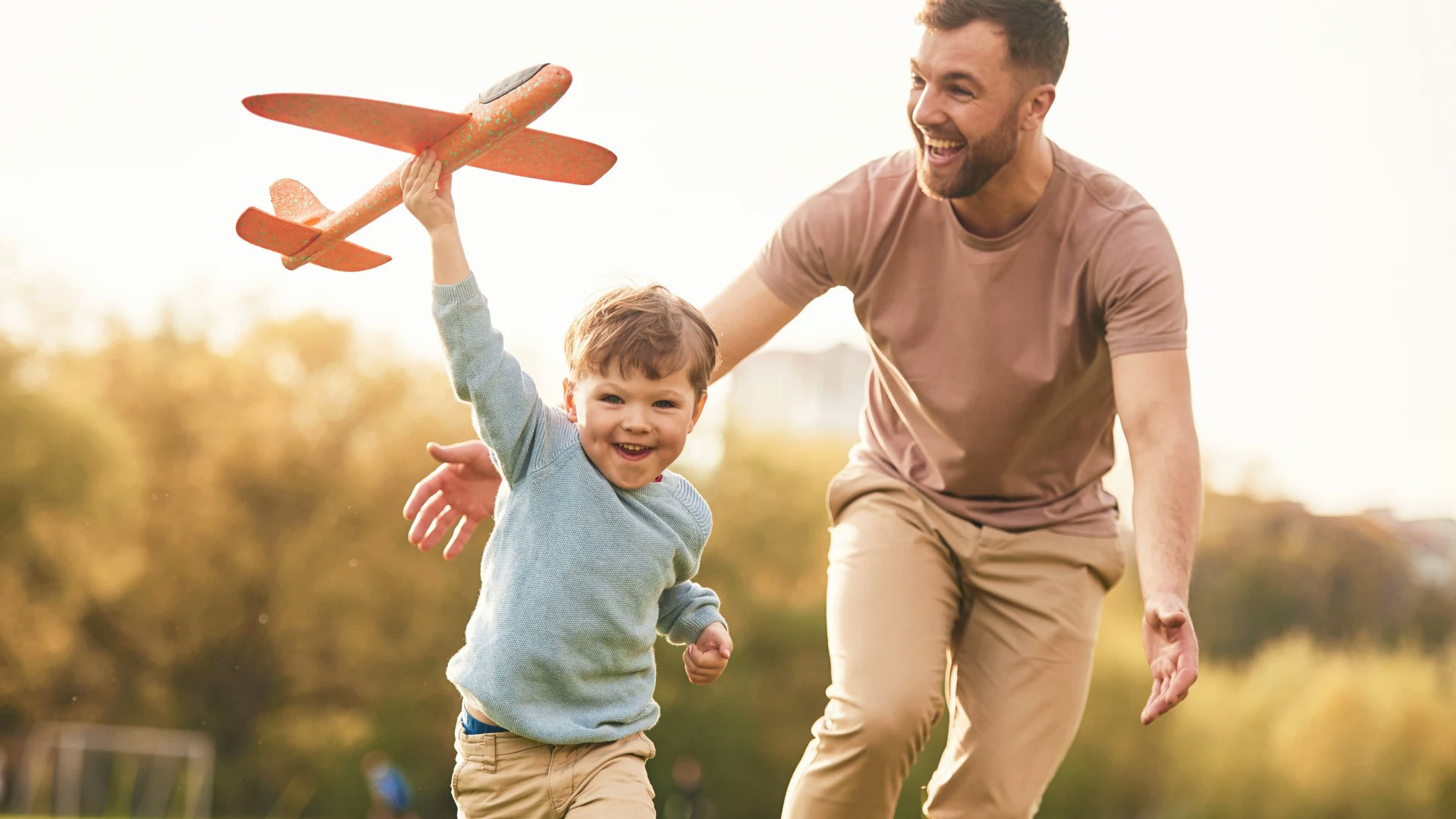 Un père et son enfant d'âge préscolaire jouent avec un jouet de modèle d'avion à l'extérieur