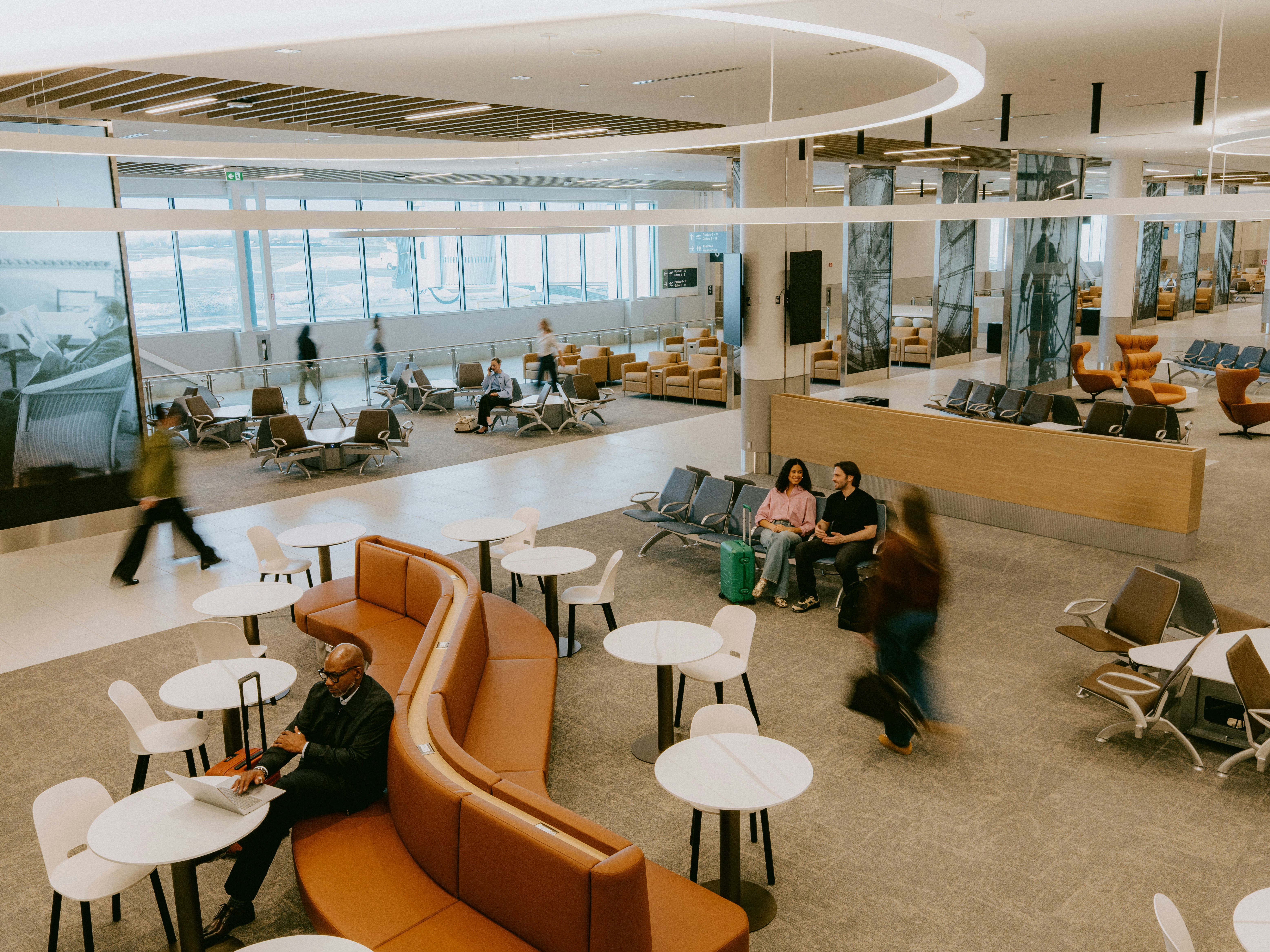 Aire d’attente du terminal du MET avec passagers assis, tables de travail et espaces lounge