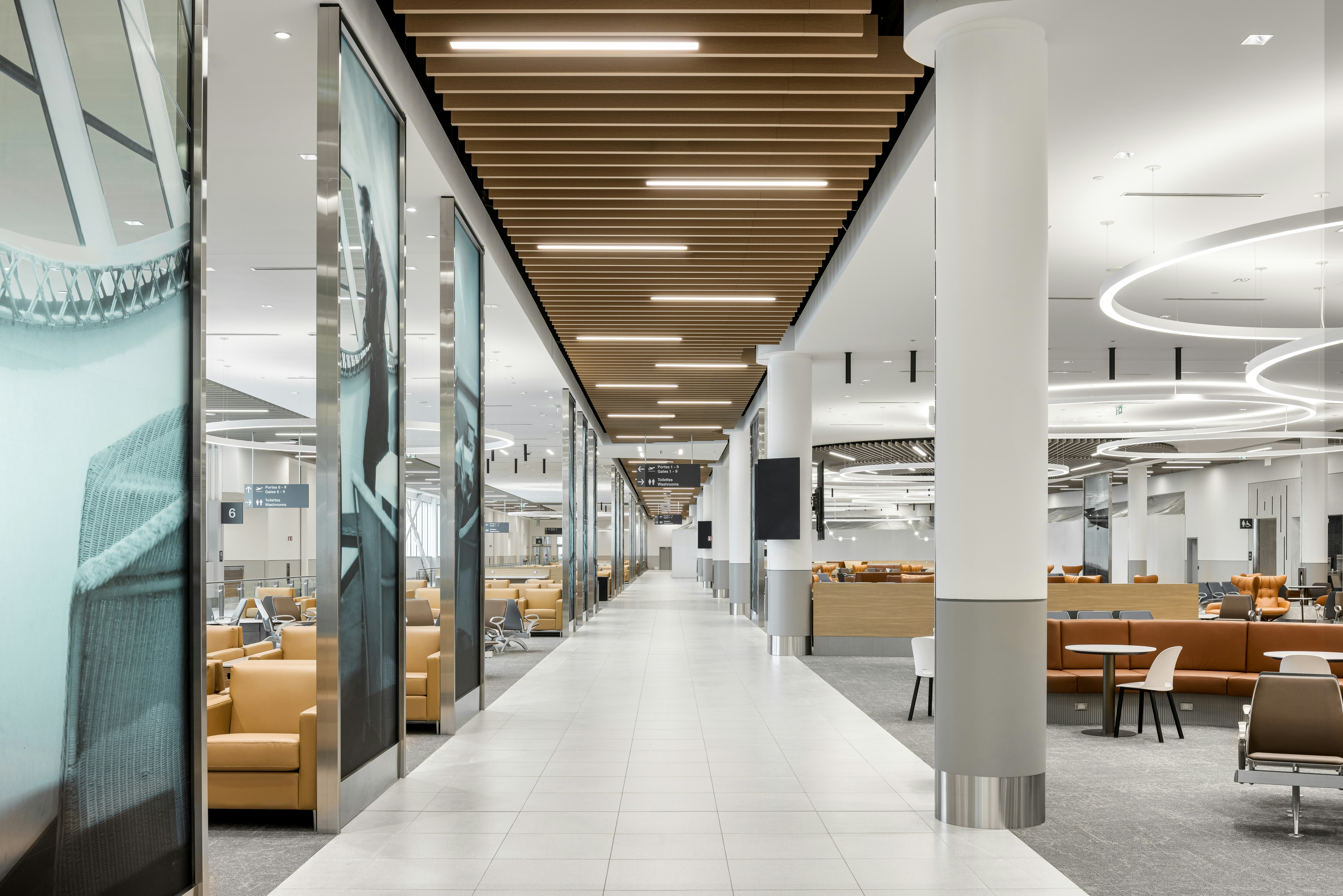 Allée centrale du terminal du MET bordée d’espaces d’attente, de colonnes et d’un plafond architectural en bois