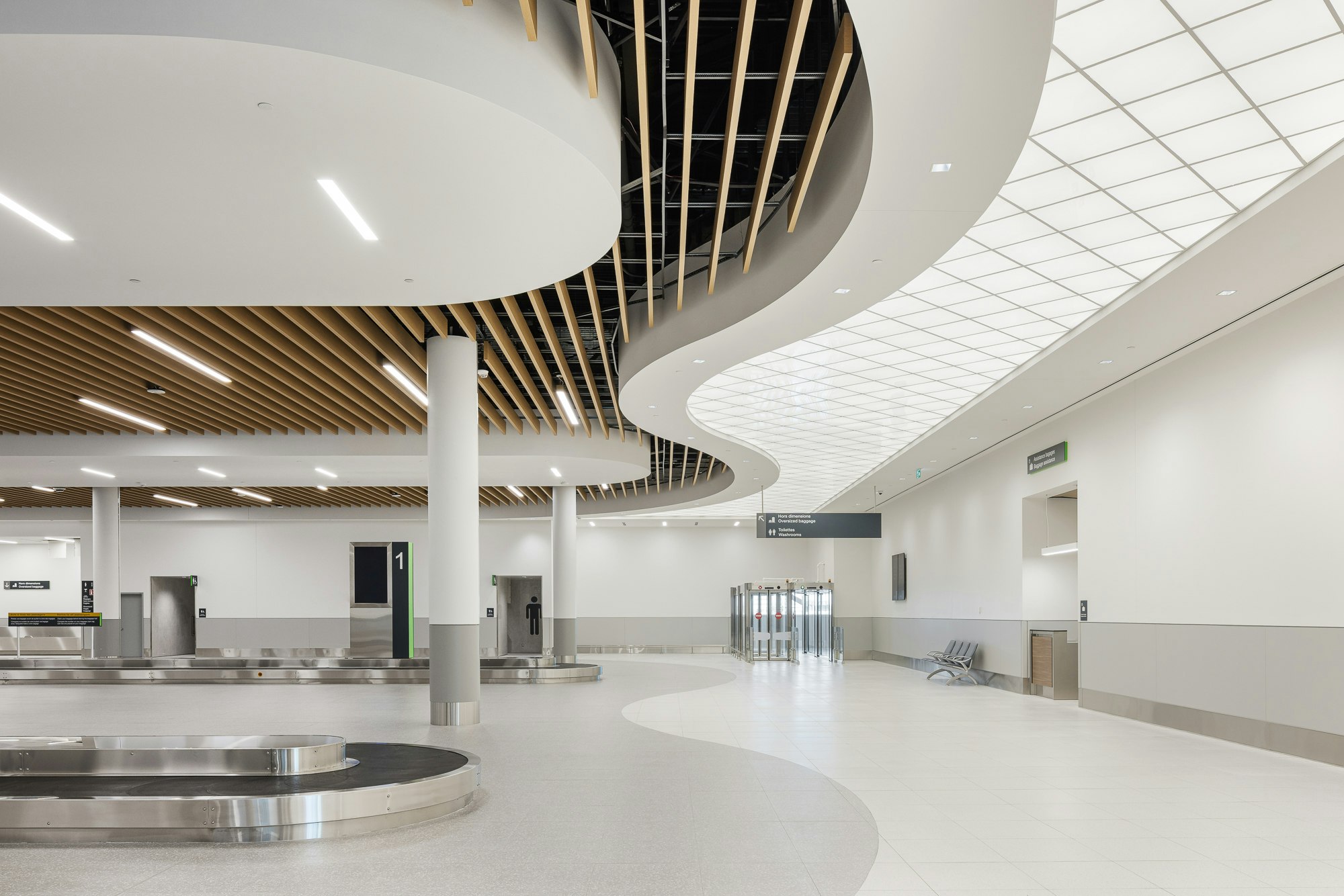 Salle de récupération des bagages du terminal du MET avec carrousels, colonnes et plafond architectural courbe