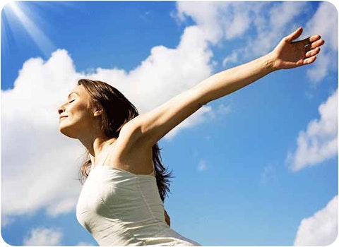 woman in white dress with arms outstretched on sunny day