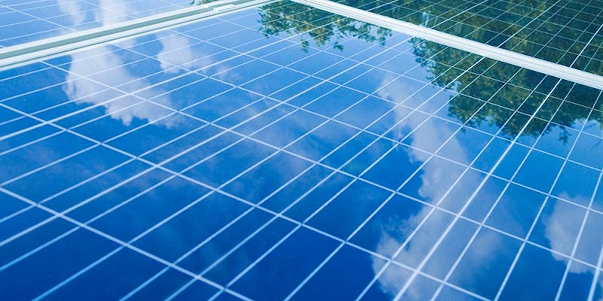 close up of 3 solar panels showing reflection of cloudy blue sky