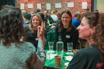 Vier lachende dames in gesprek.
