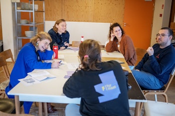 Mensen zitten rond een tafel en lachen.
