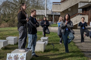 Groep mensen die buiten in een yogapose staan.