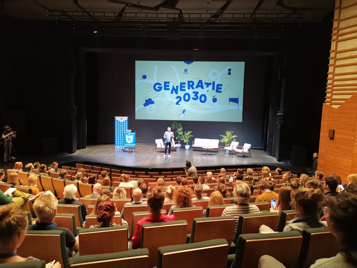 Volle zaal mensen kijkt naar een voorstelling van Generatie 2030