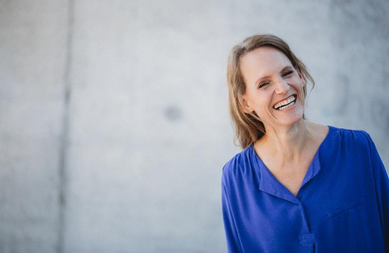 A droite de l'image, une femme souriante en chemisier bleu