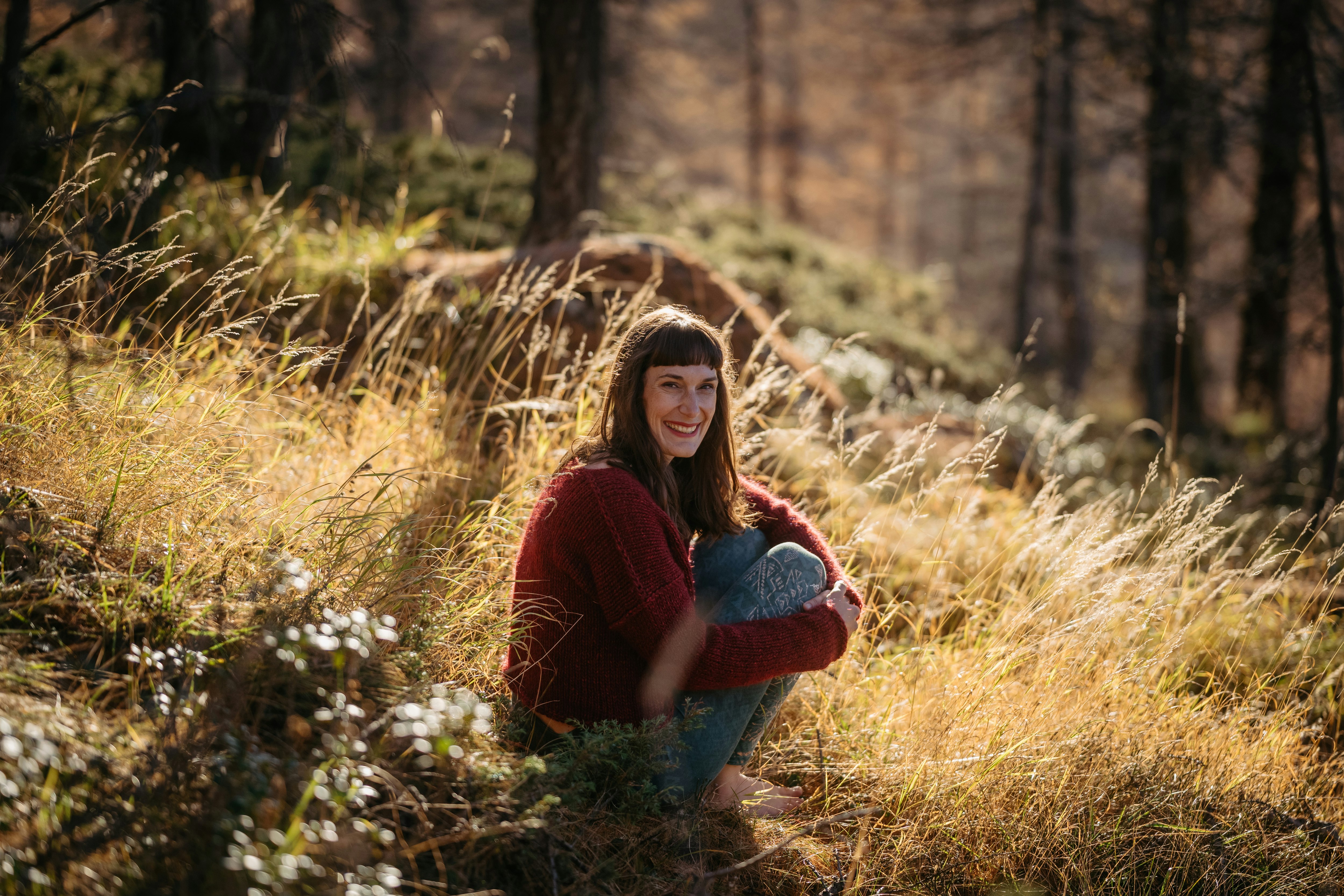 Junge Frau sitzt in einer Waldlichtung