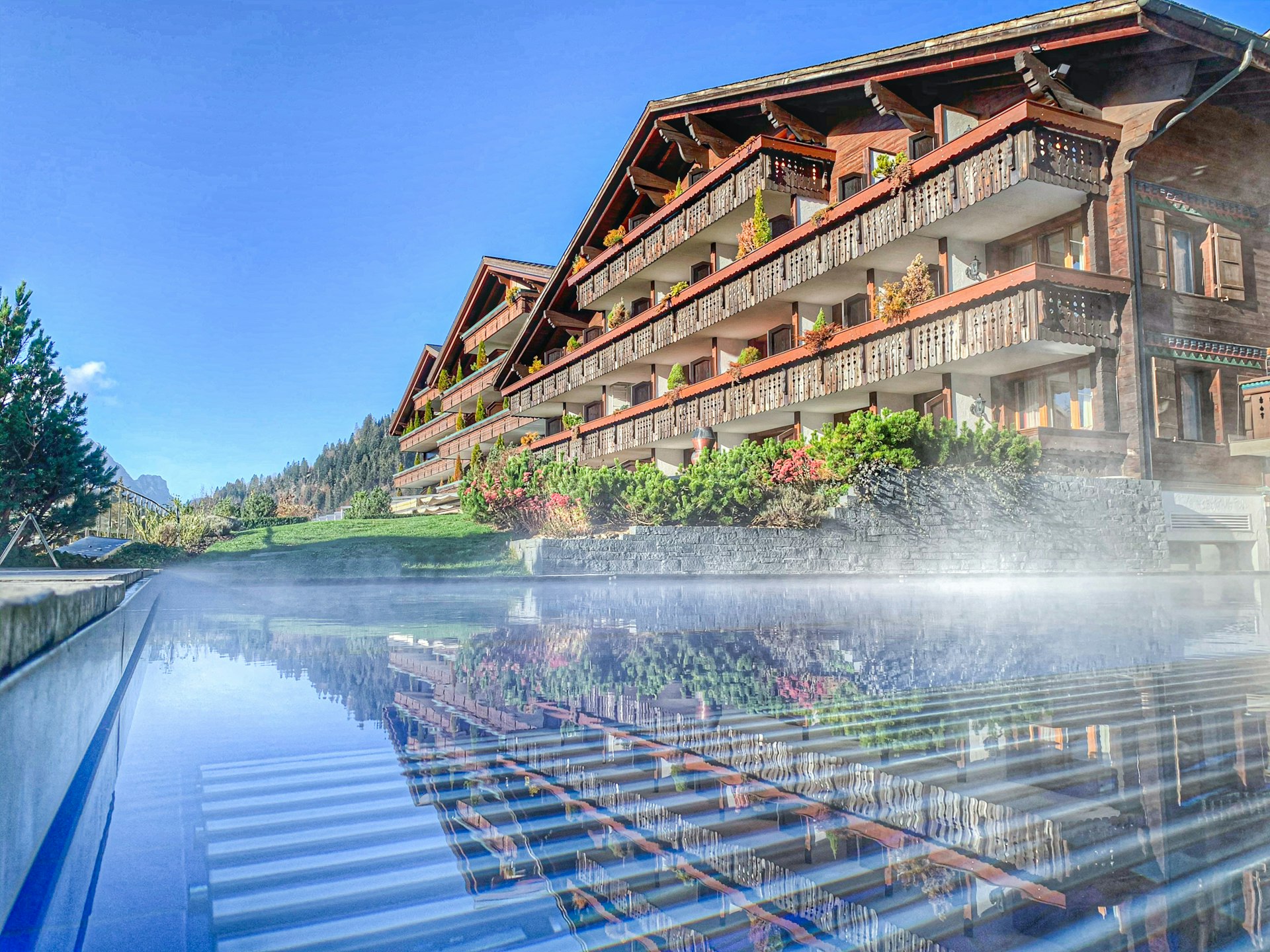 ERMITAGE Sportpool Outdoor in den Bergen mit Chalet im Hintergrund