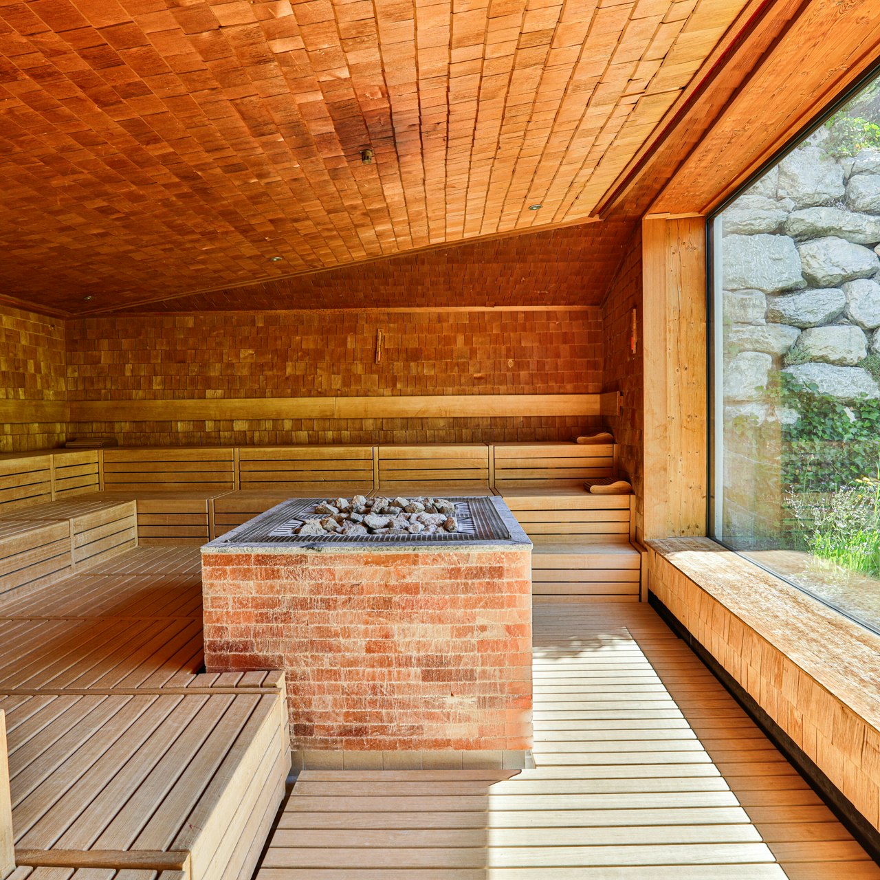 Panoramic sauna at the Hotel Ermitage Spacious sauna completely lined with wood, sauna stove in the centre, large panoramic window to the garden