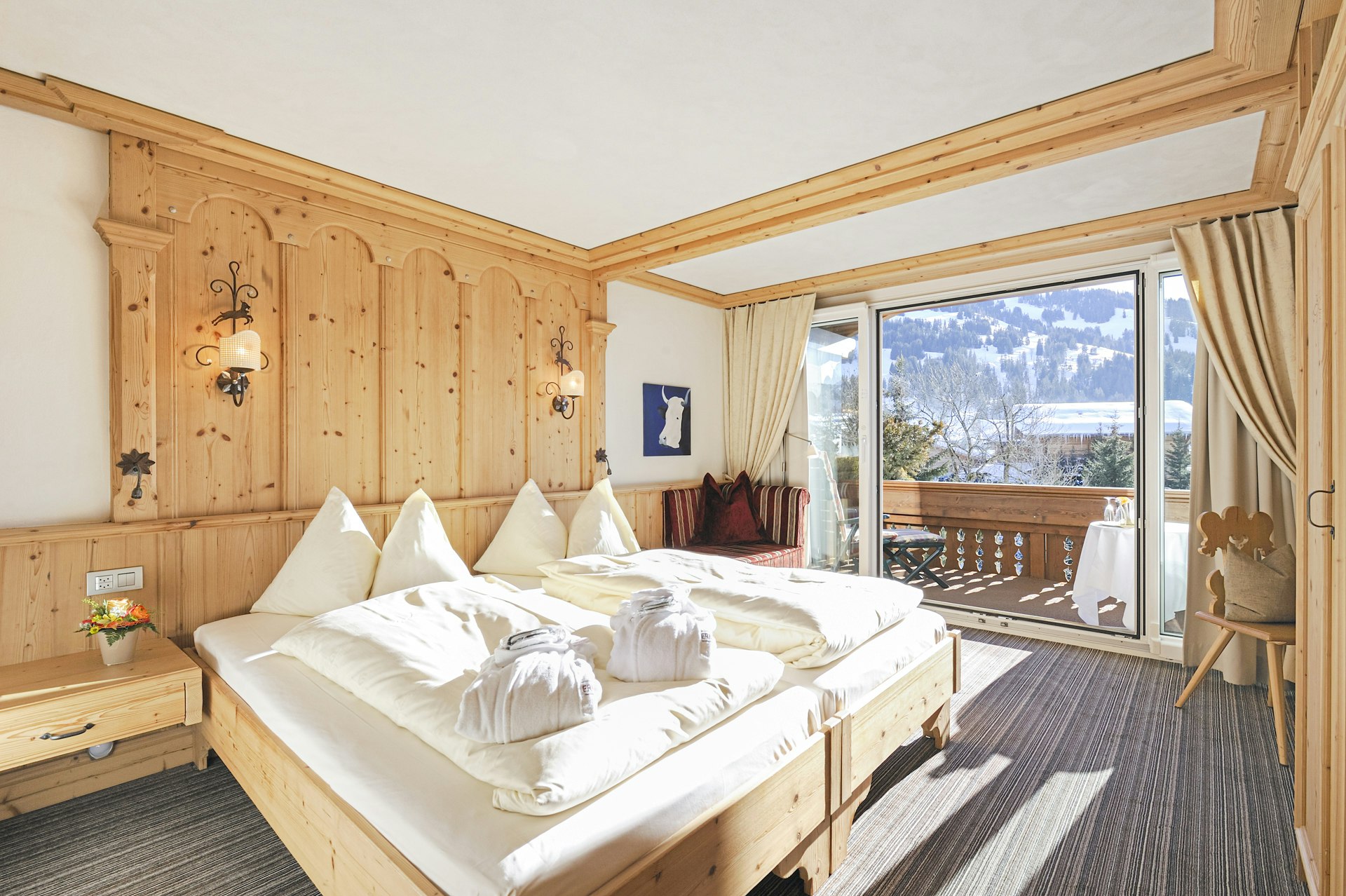 Sonniges Schlafzimmer mit Doppelbett, Holztäfer, Teppichboden und Balkon