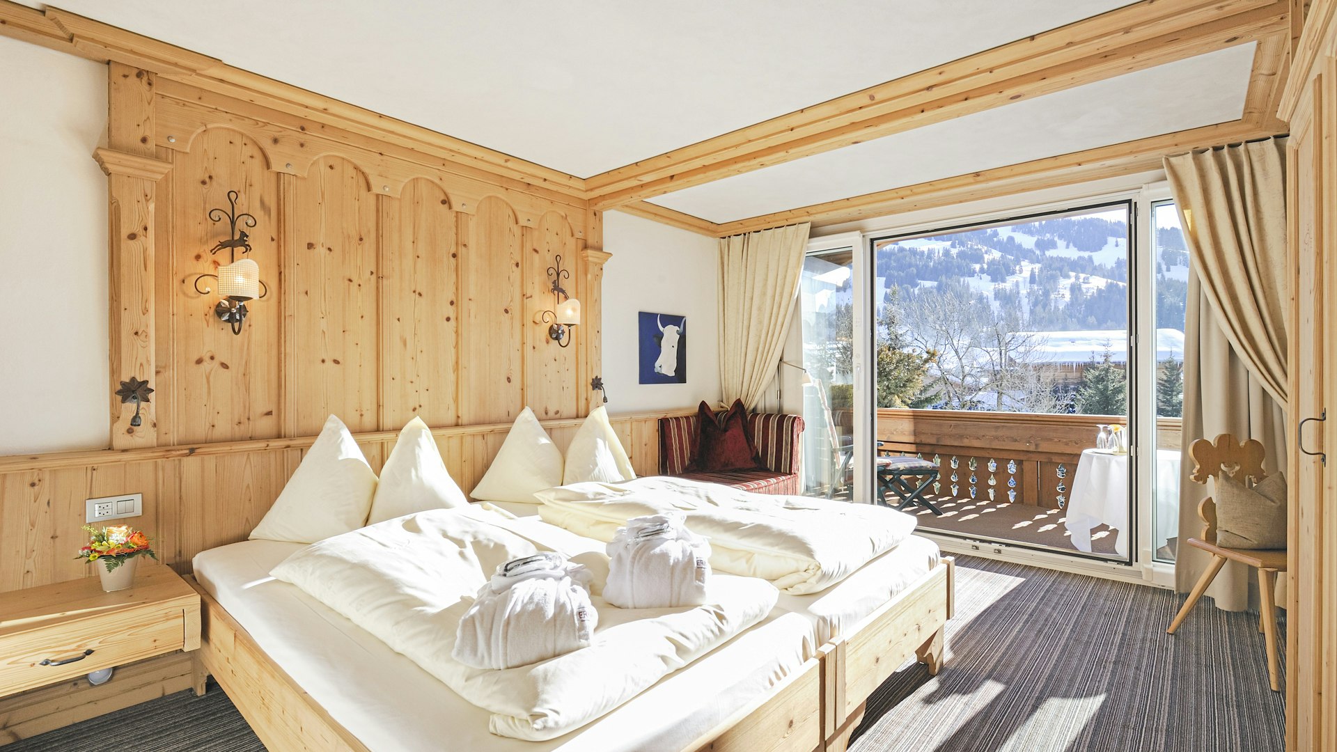 Eggli Suite à l'hôtel Ermitage Chambre à coucher ensoleillée avec lit double, boiseries, moquette et balcon