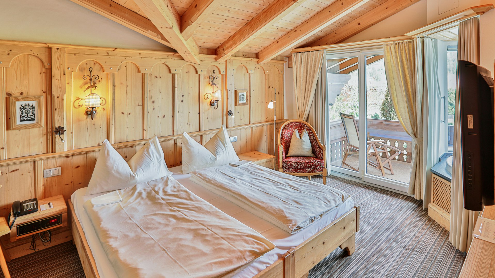 Suite Wellness à l'hôtel Ermitage Chambre à coucher avec deux lits séparés, murs en bois, moquette et balcon