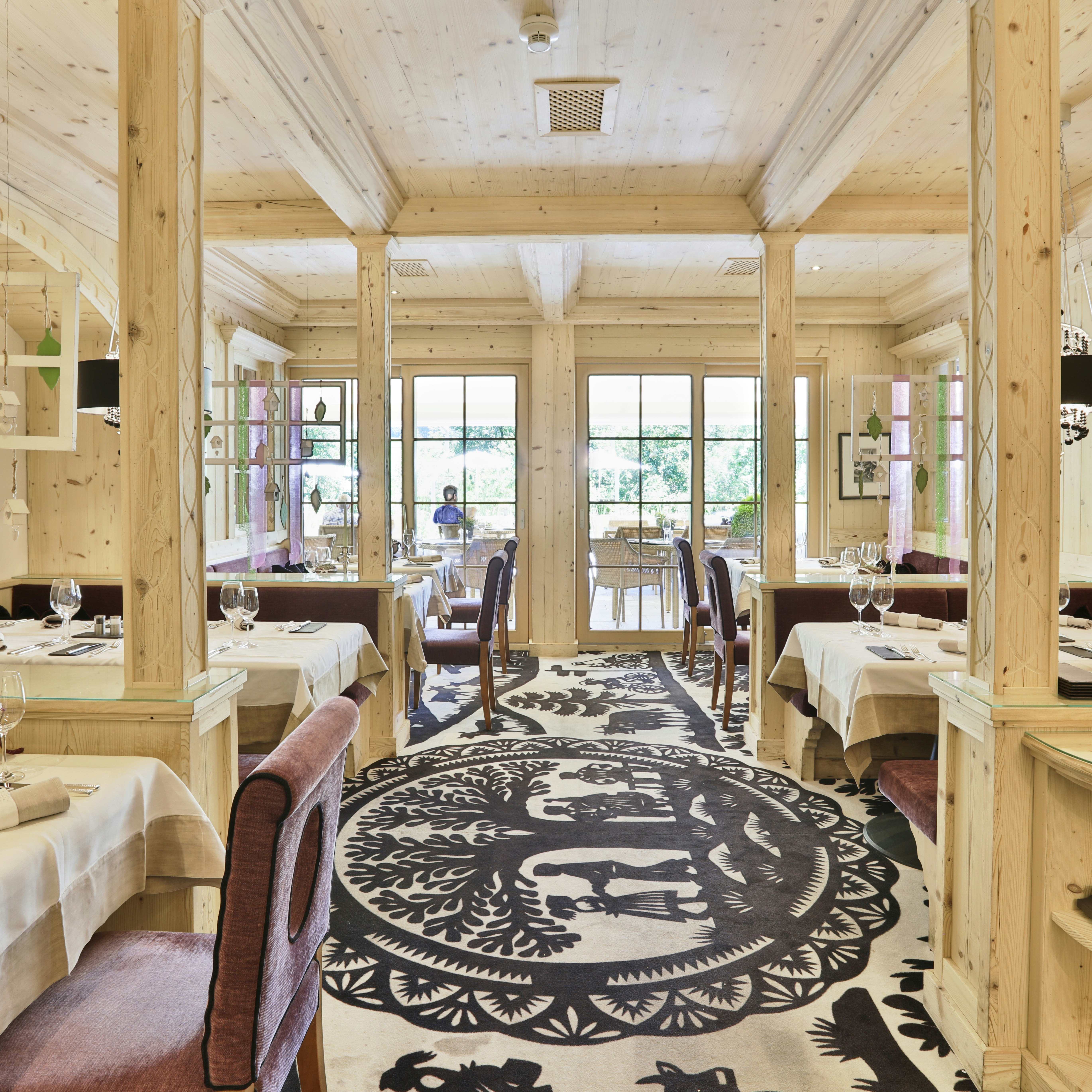 Ermitage Stube Gaststube ganz aus hellem Holz gearbeitet mit Teppich mit Scherenschnittmuster