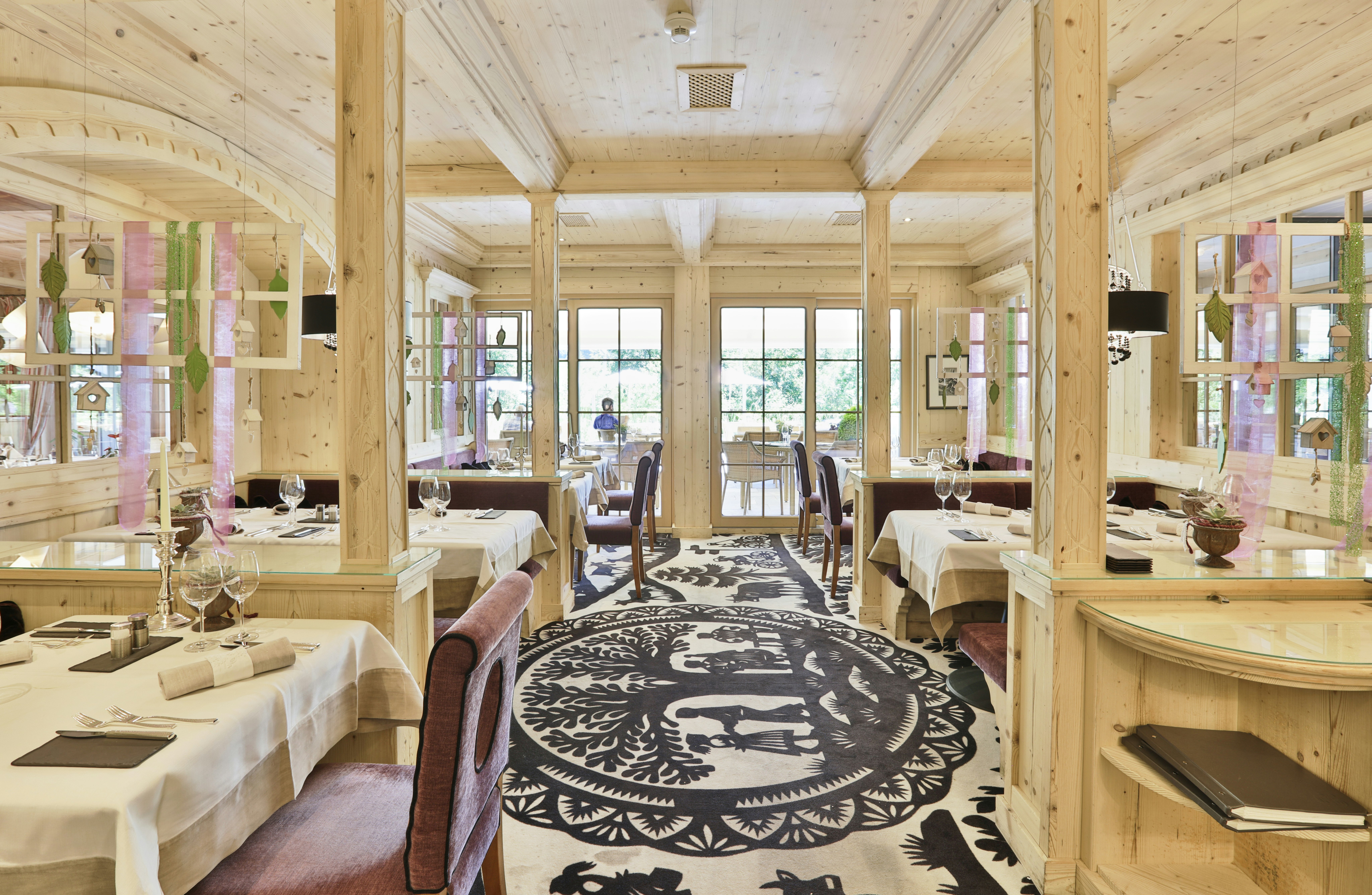 Salle de restaurant entièrement en bois clair avec tapis en papier découpé.