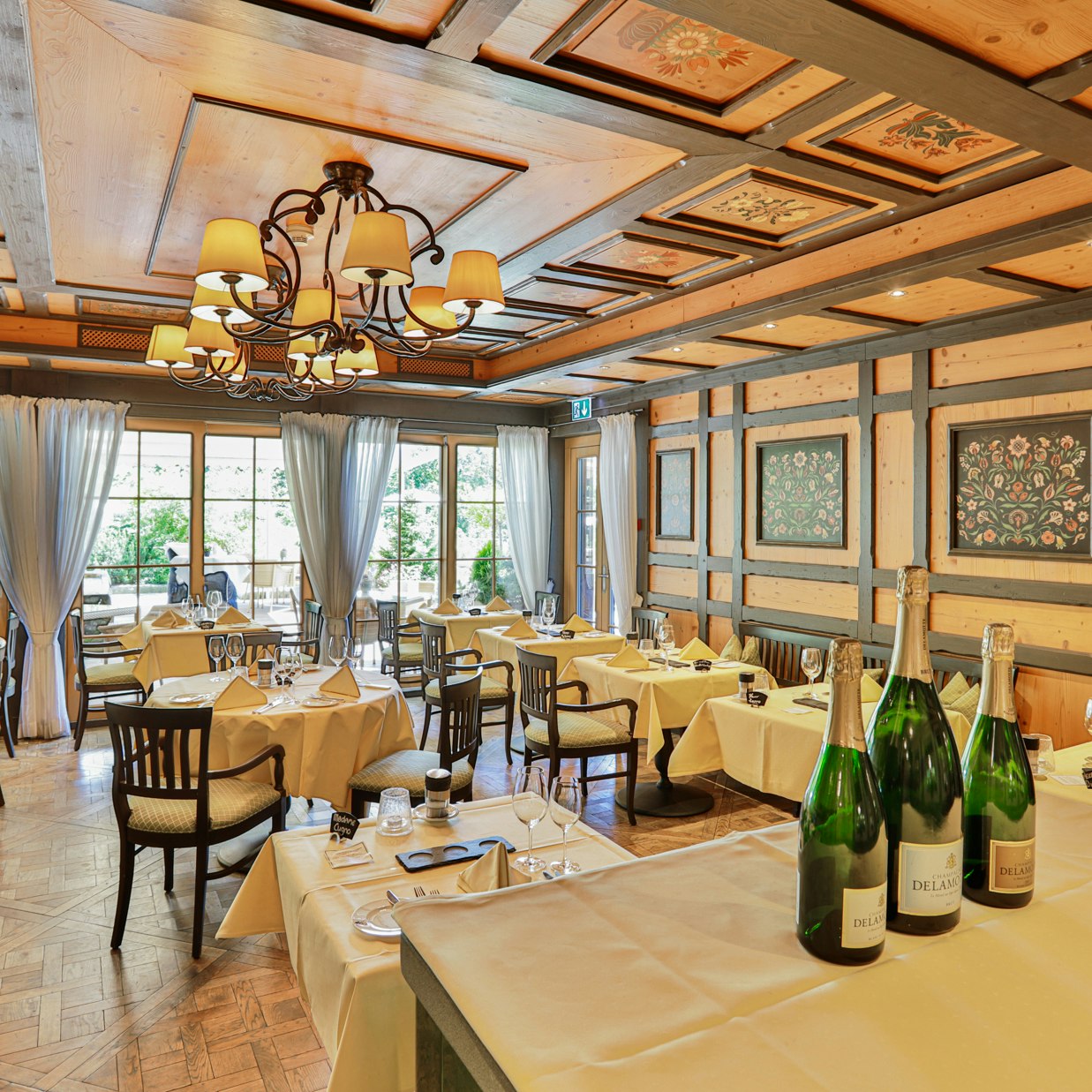 Lutz-Stube im Hotel Ermitage Ganz mit Holz ausgekleideter Raum mit Dekorpaneelen, gedeckte Tische, grosse Fensterfront