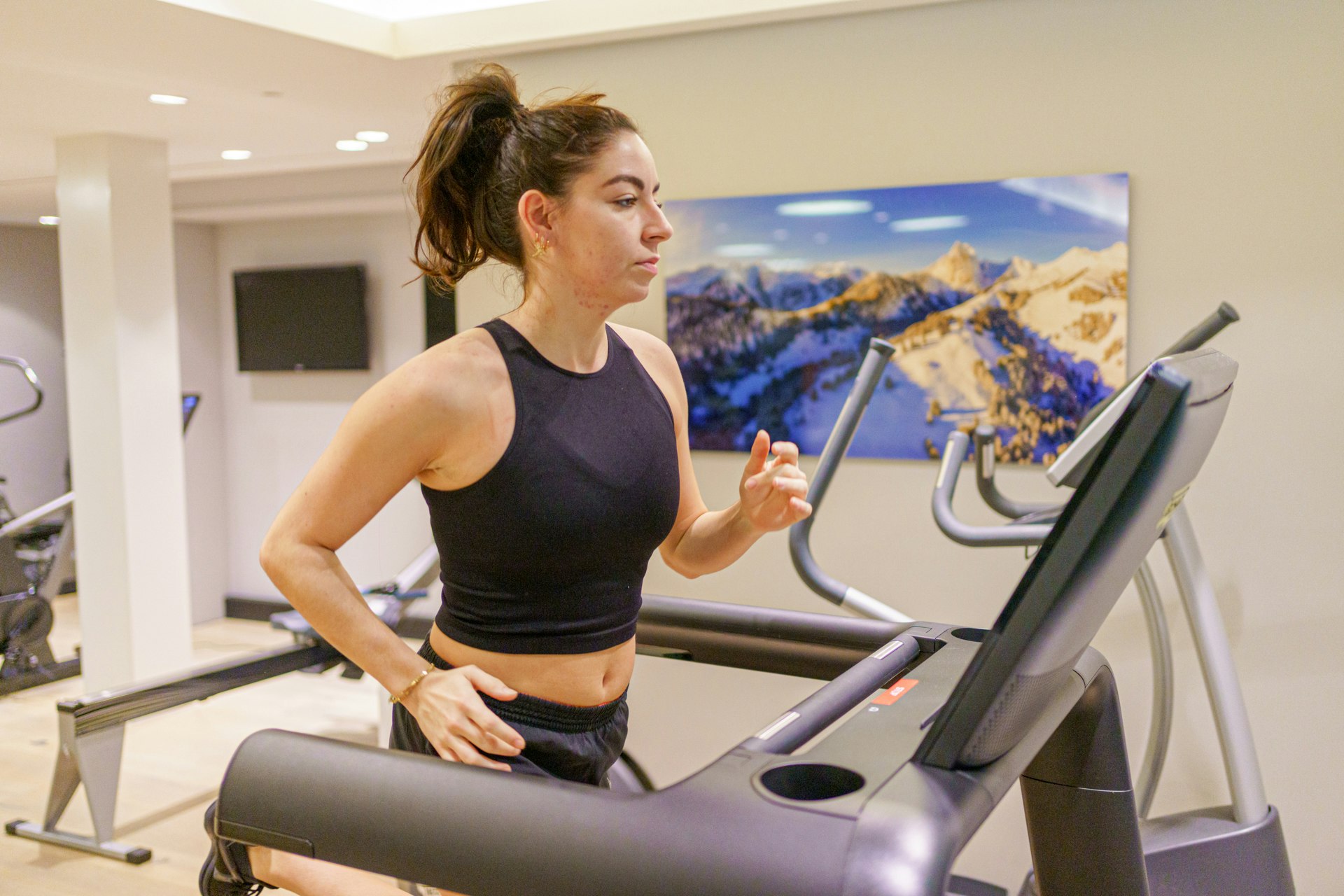 Une femme court sur un tapis roulant dans une salle de fitness