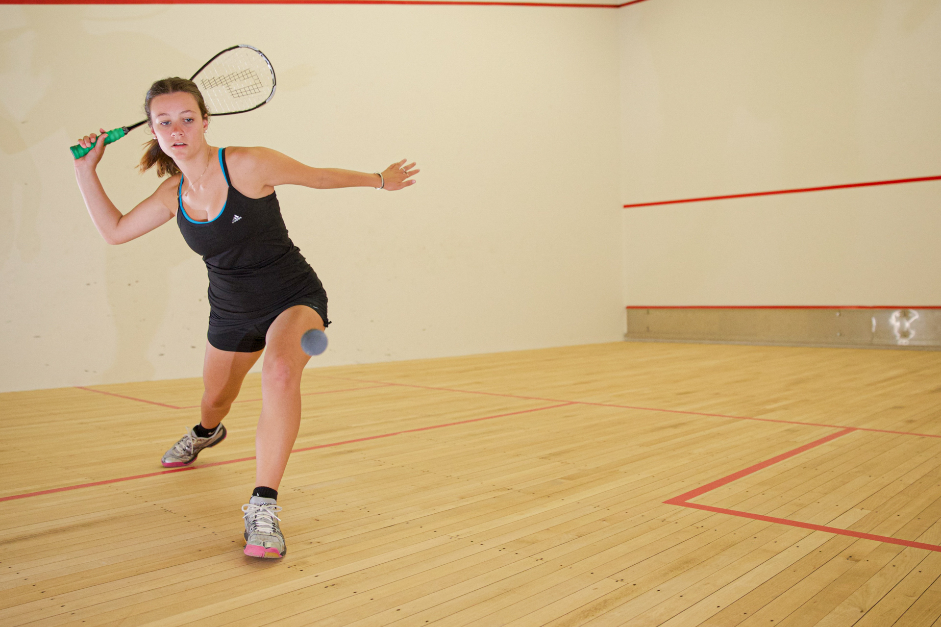 Junge Frau spielt Squash in einer Halle