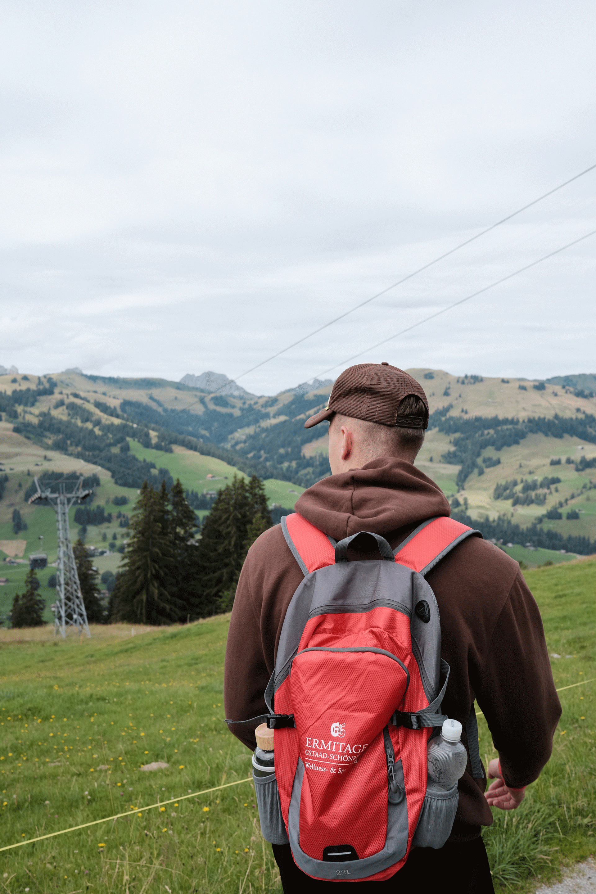 Ein Mann mit rotem Ermitage-Rucksack vor Berglandschaft