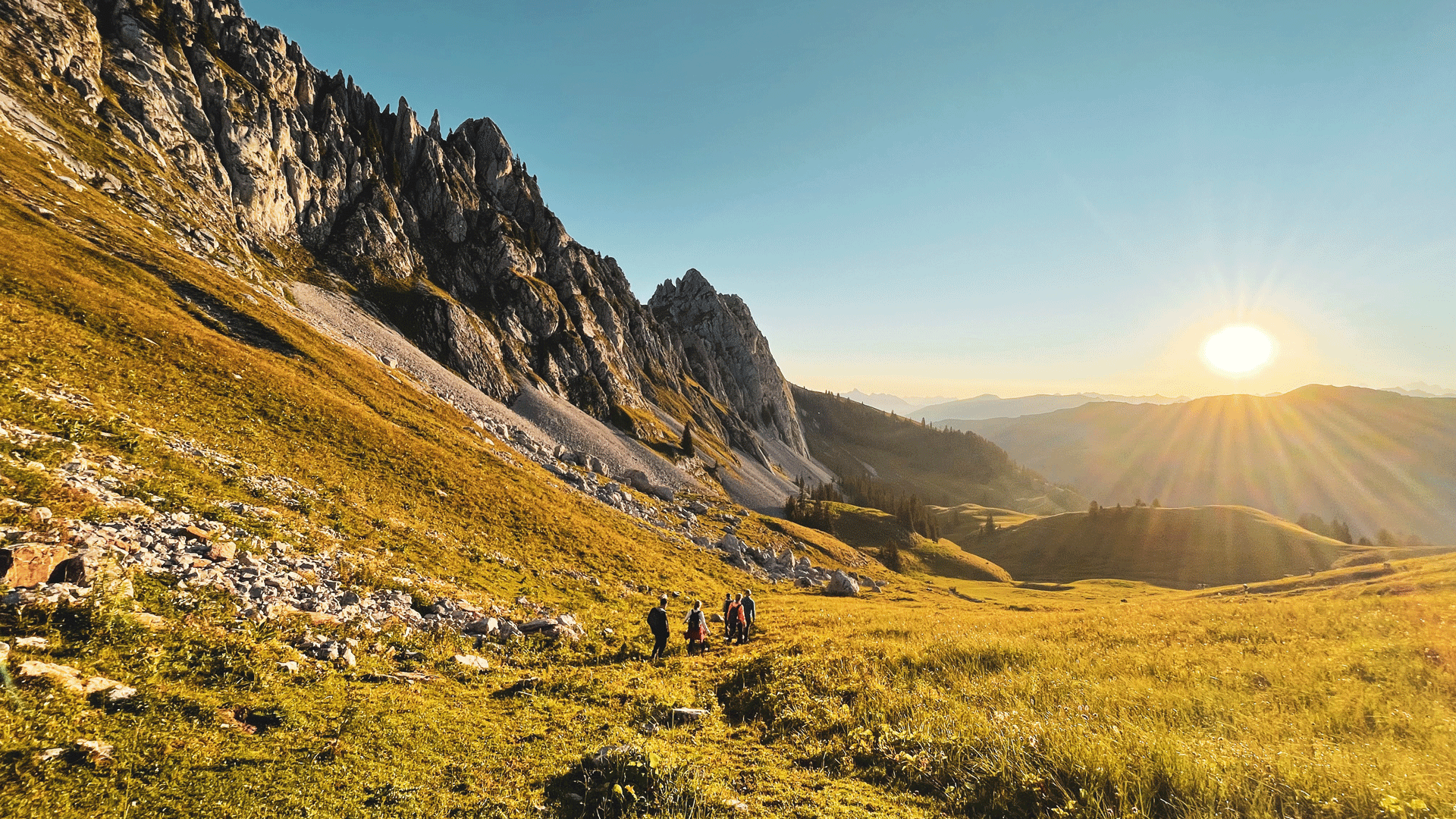 Randonnée avec les guides nature de l'hôtel Ermitage Randonneurs dans un paysage de montagne au lever du soleil