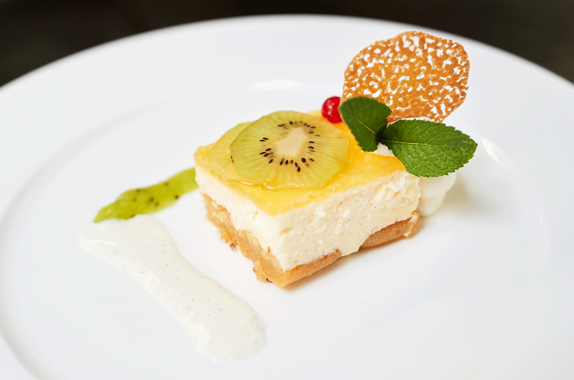 Geschichtetes und dekoriertes Dessert mit Rahm und einer Kiwischeibe
