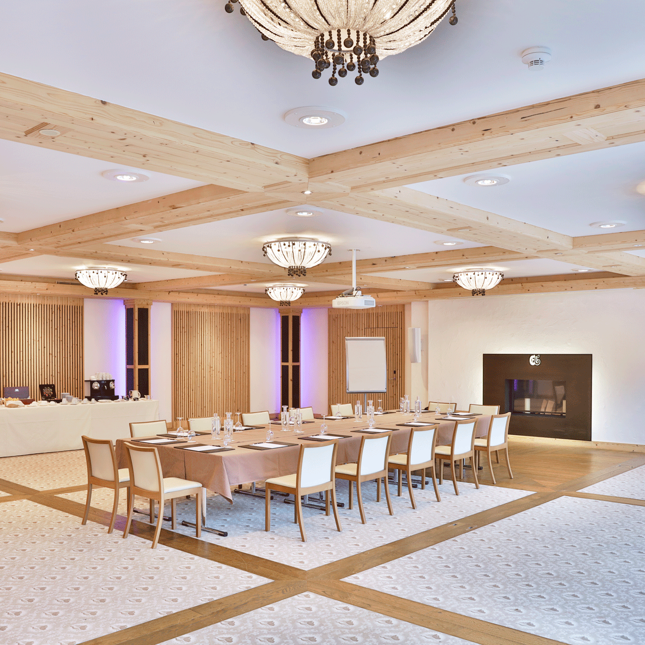 Salon Festival seminar room at the Hotel Ermitage Room with glass lighting, a long table with writing pads and chairs and a buffet