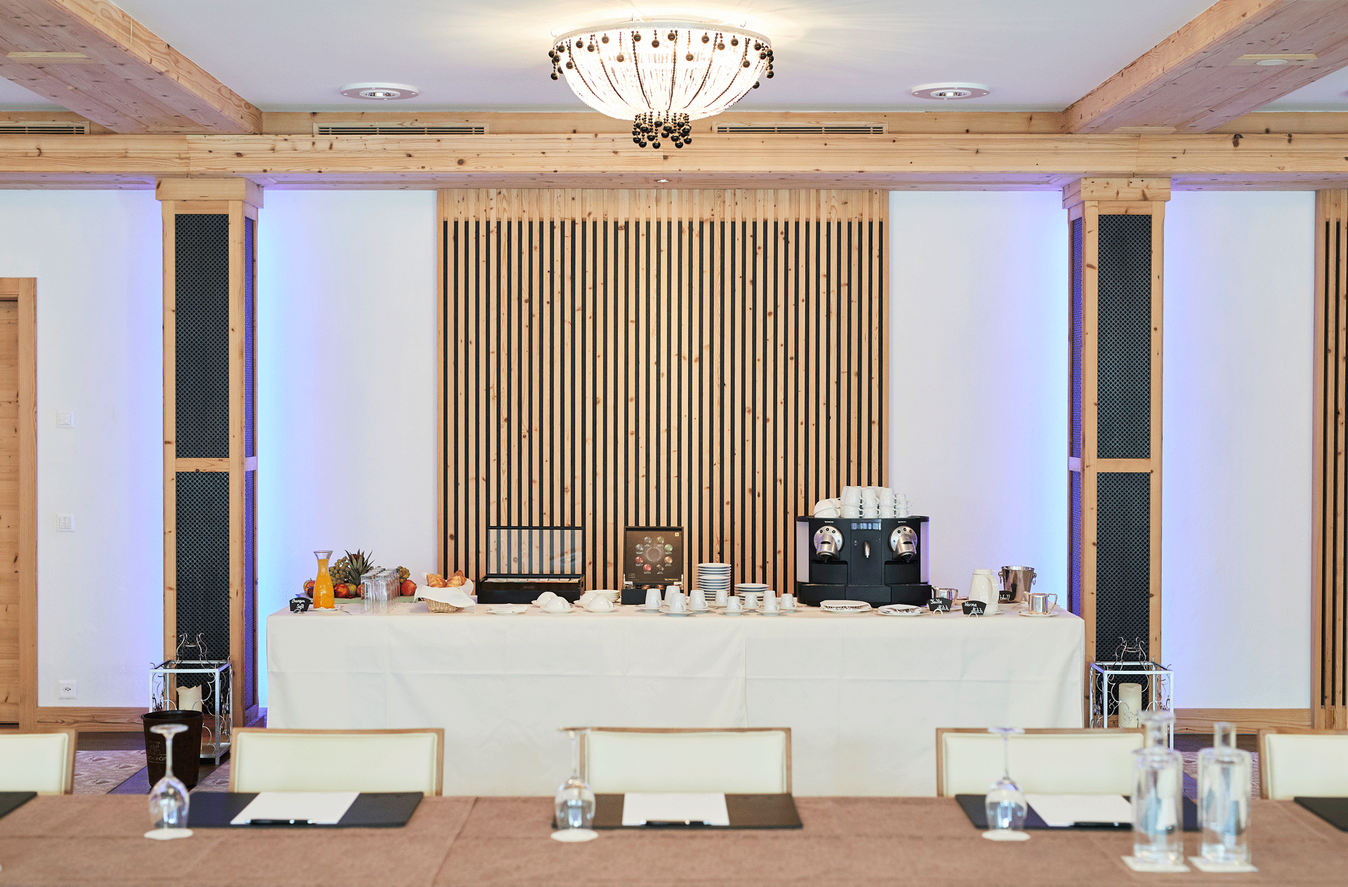 Saal mit Glasleuchte, einem langen Tisch mit Schreibunterlagen und einem Buffet
