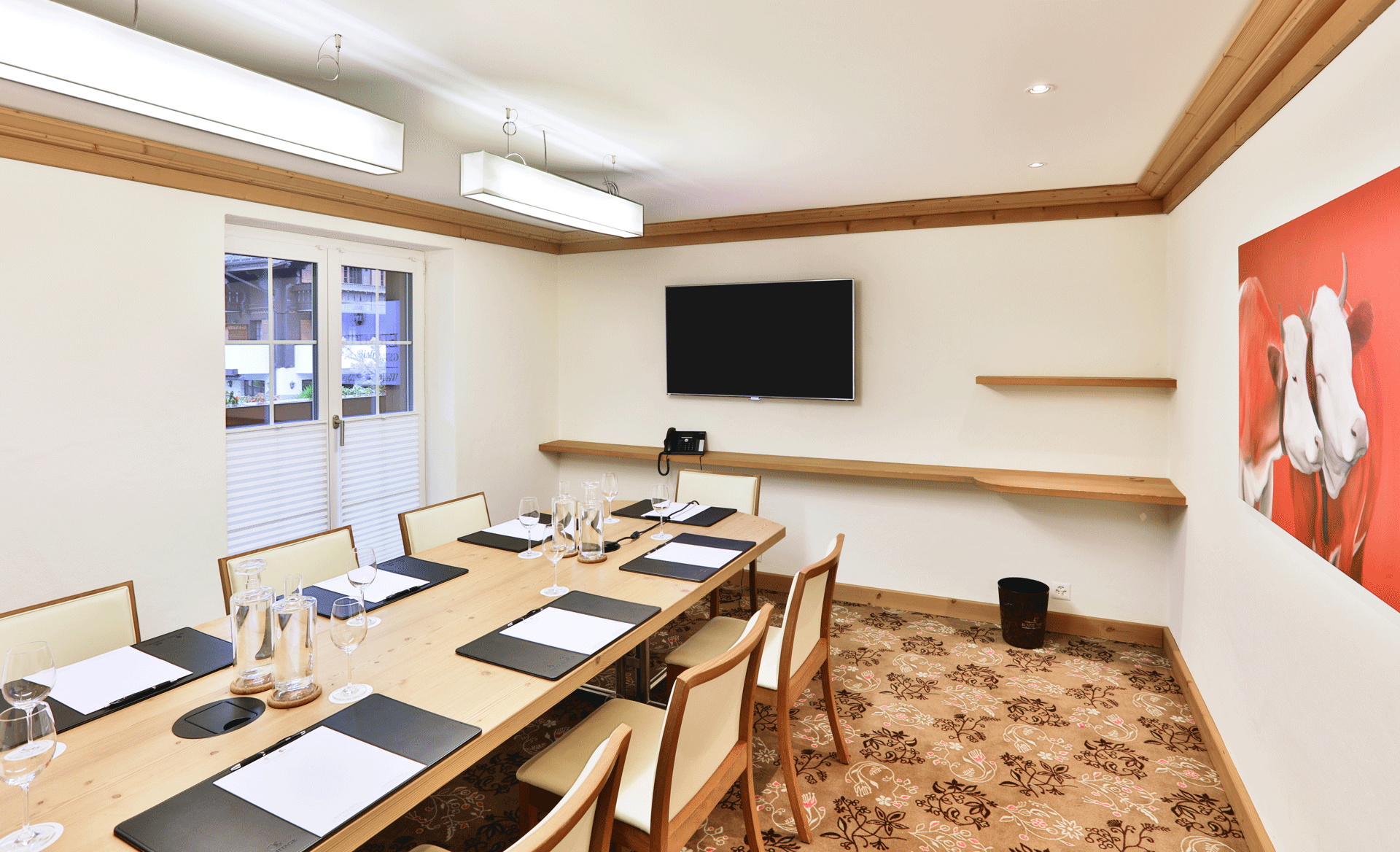 Salle avec moquette, néons et grande table avec sous-mains et chaises