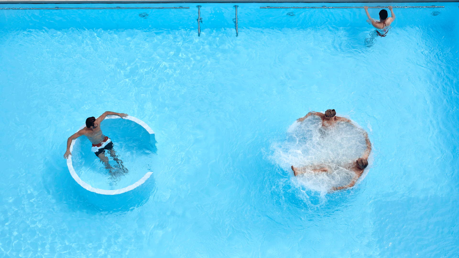 Bird's eye view of the saltwater pool at the Hotel Ermitage Two whirlpools in an outdoor pool, with three people in them, seen from above