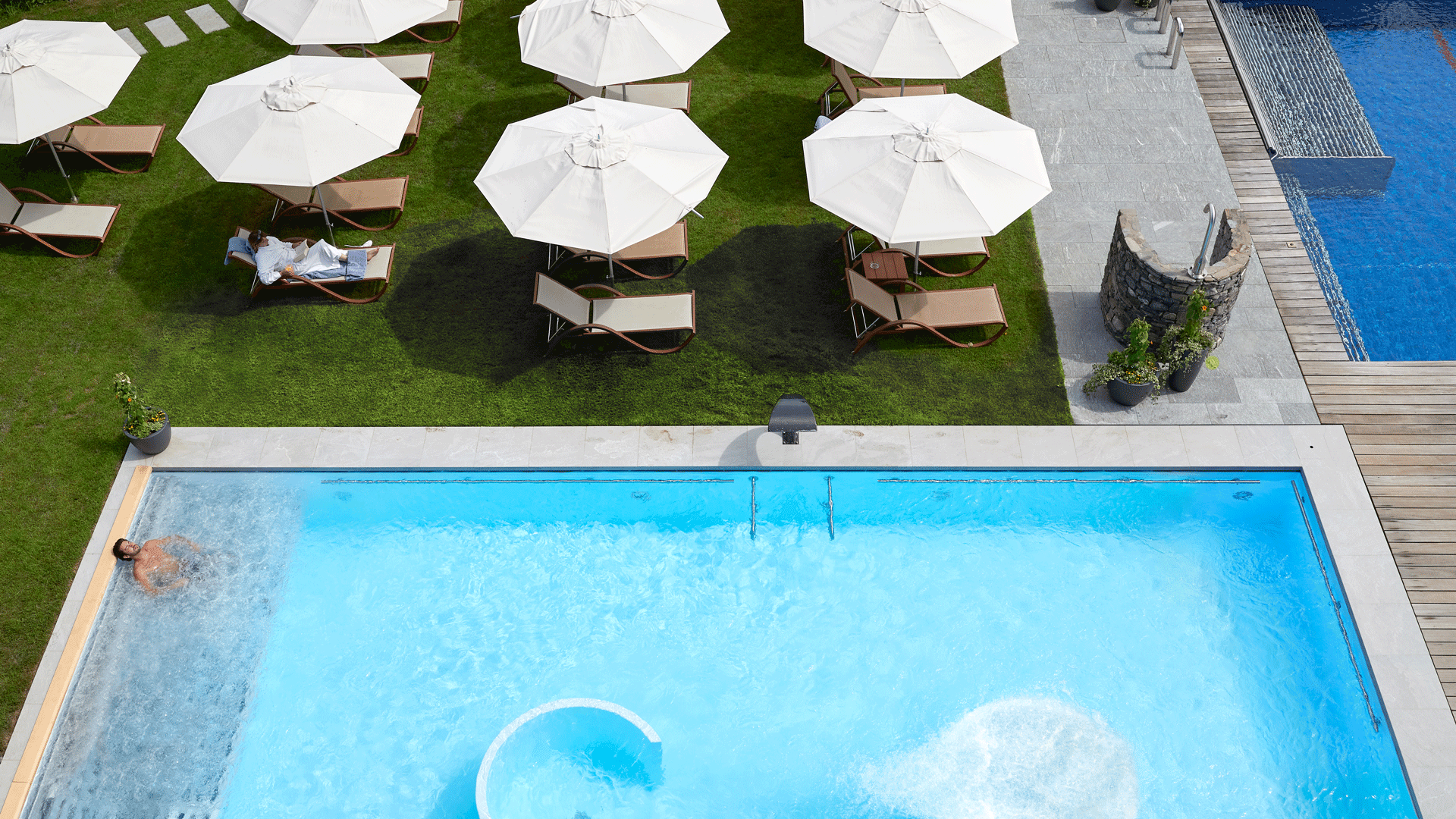 Sol and sports pool at the Hotel Ermitage A light blue and dark blue pool and a lawn with sunbeds and parasols