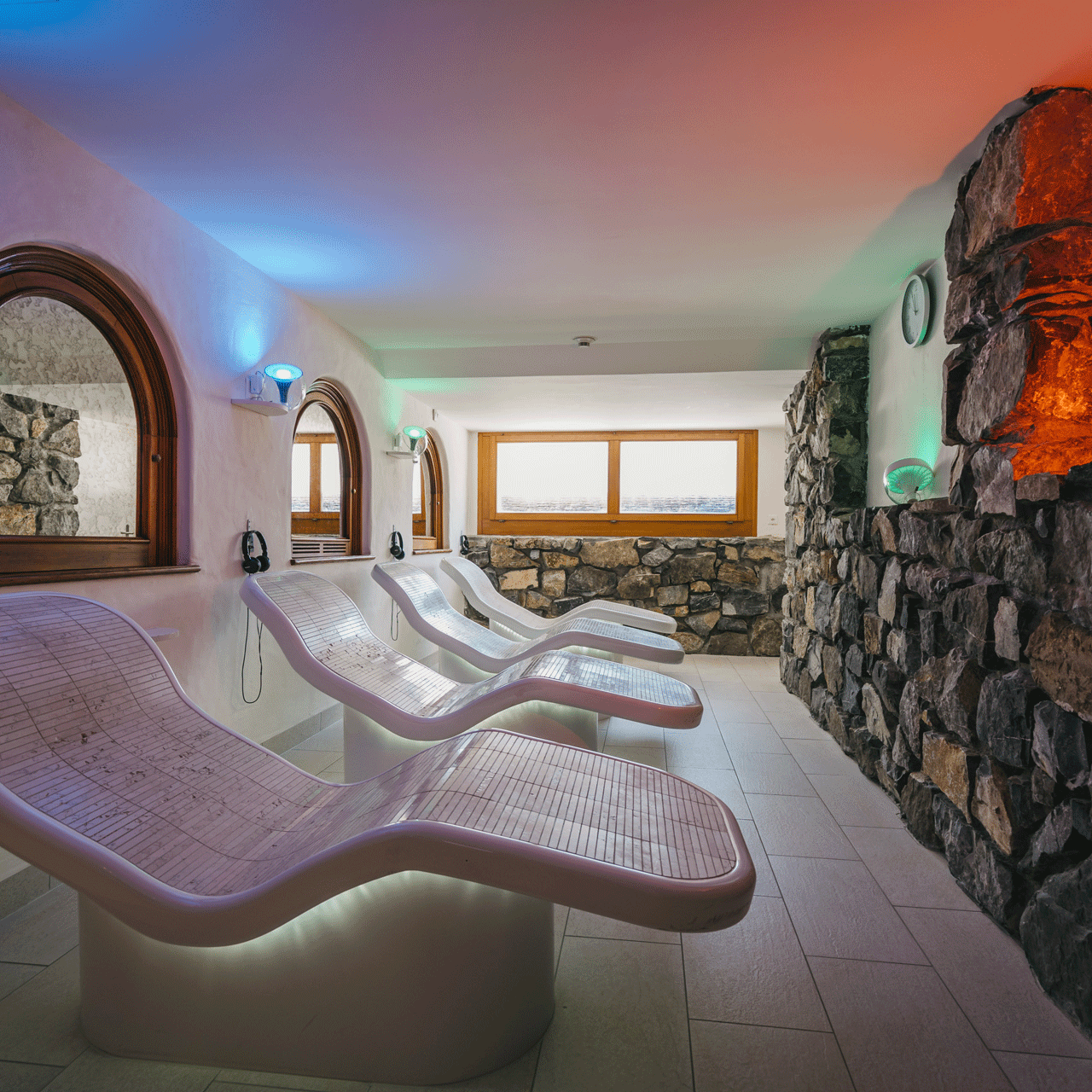 Relaxation room at the Hotel Ermitage Red and blue illuminated room with rough stone walls and loungers