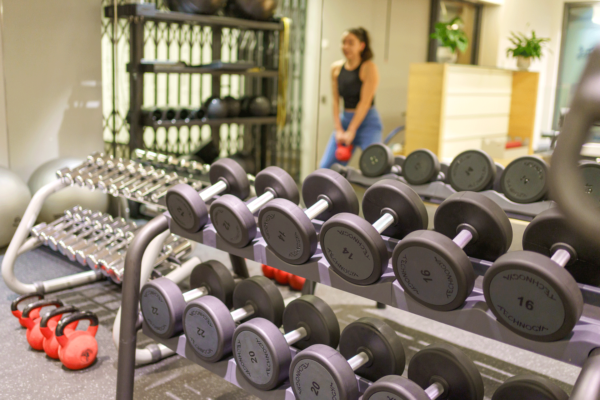 Vordergrund Gewichte, Hintergrund Dame beim Training