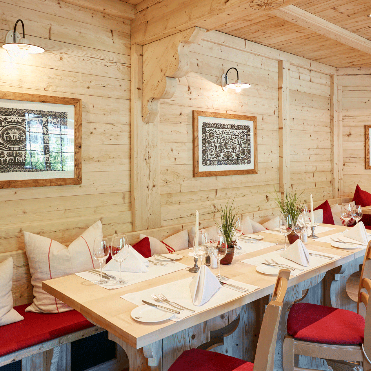 Saane-Stube im Hotel Ermitage In hellem Holz verkleidetes Restaurant, gedeckte Holztische, an der Wand Scherenschnitte