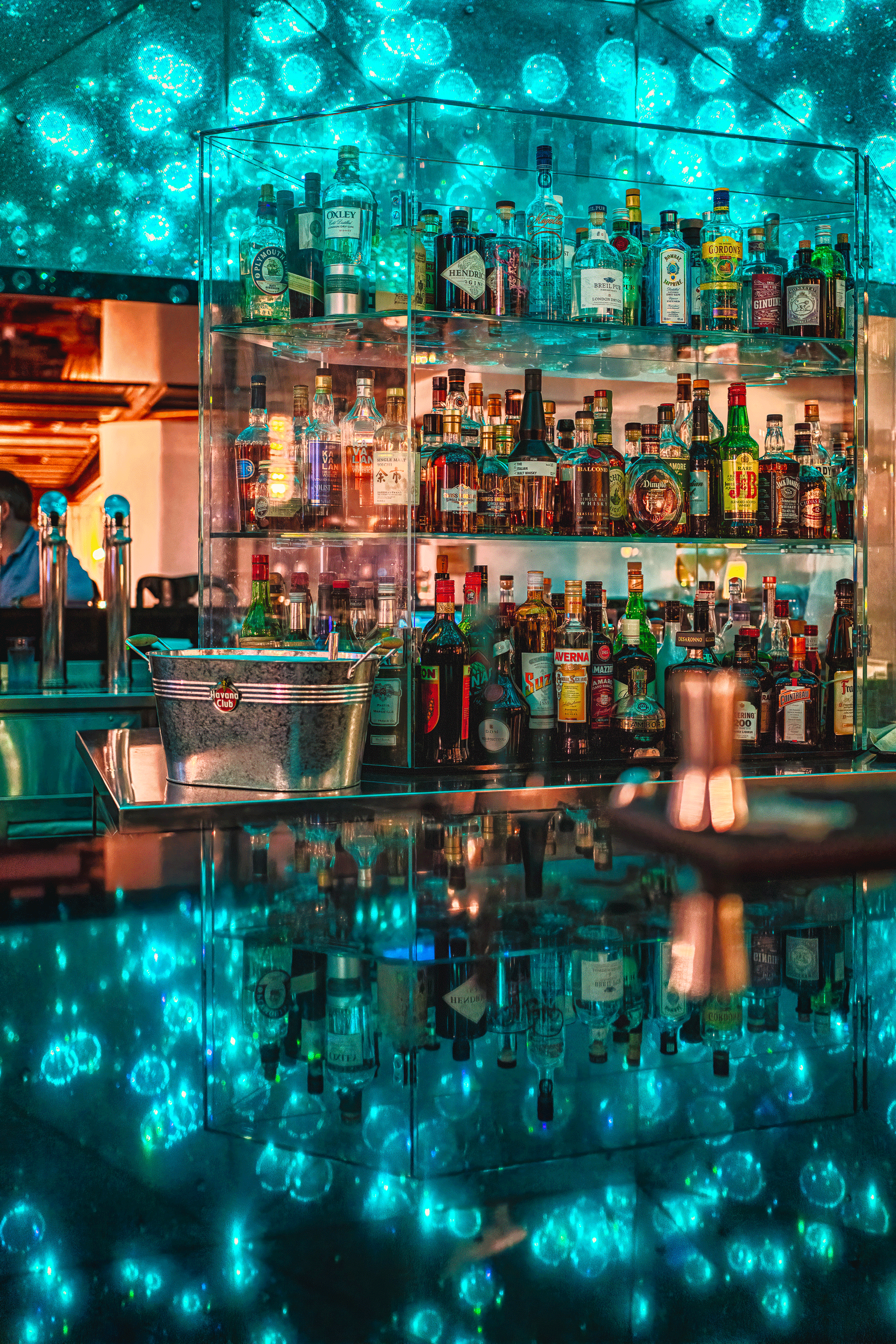 Bar mit spiegelndem Tresen und blau beleuchteten funkelnden Glassteinen