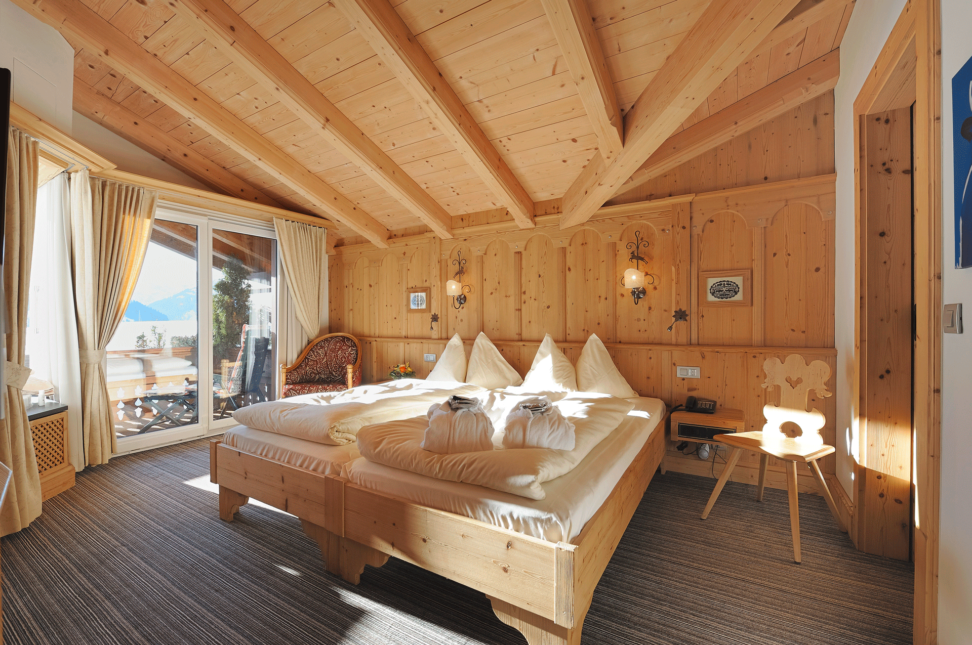 Schlafzimmer mit zwei getrennten Betten, Holzwänden, Teppichboden und Balkon