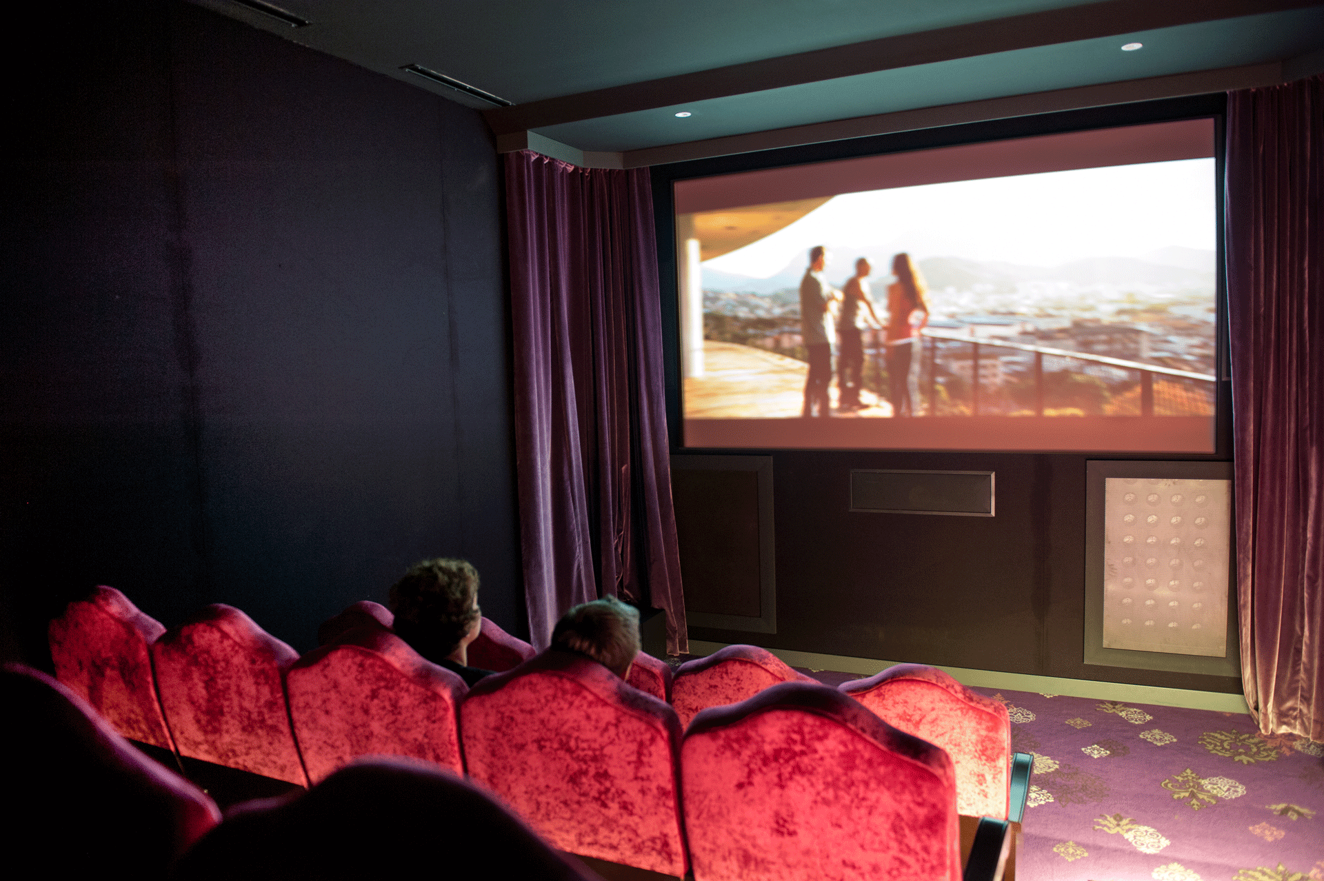 Kino mit roten Plüschsesseln, auf der Leinwand läuft ein Film