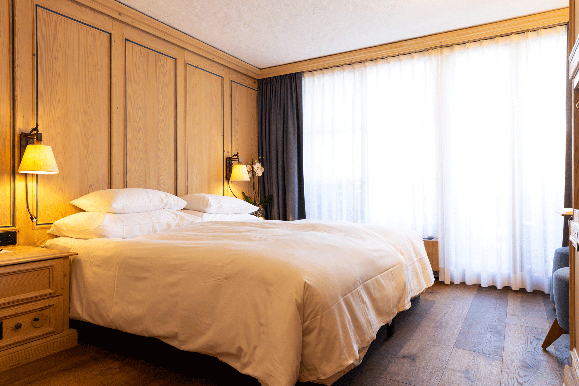 Chambre avec lambris et plancher en bois avec lit double et balcon