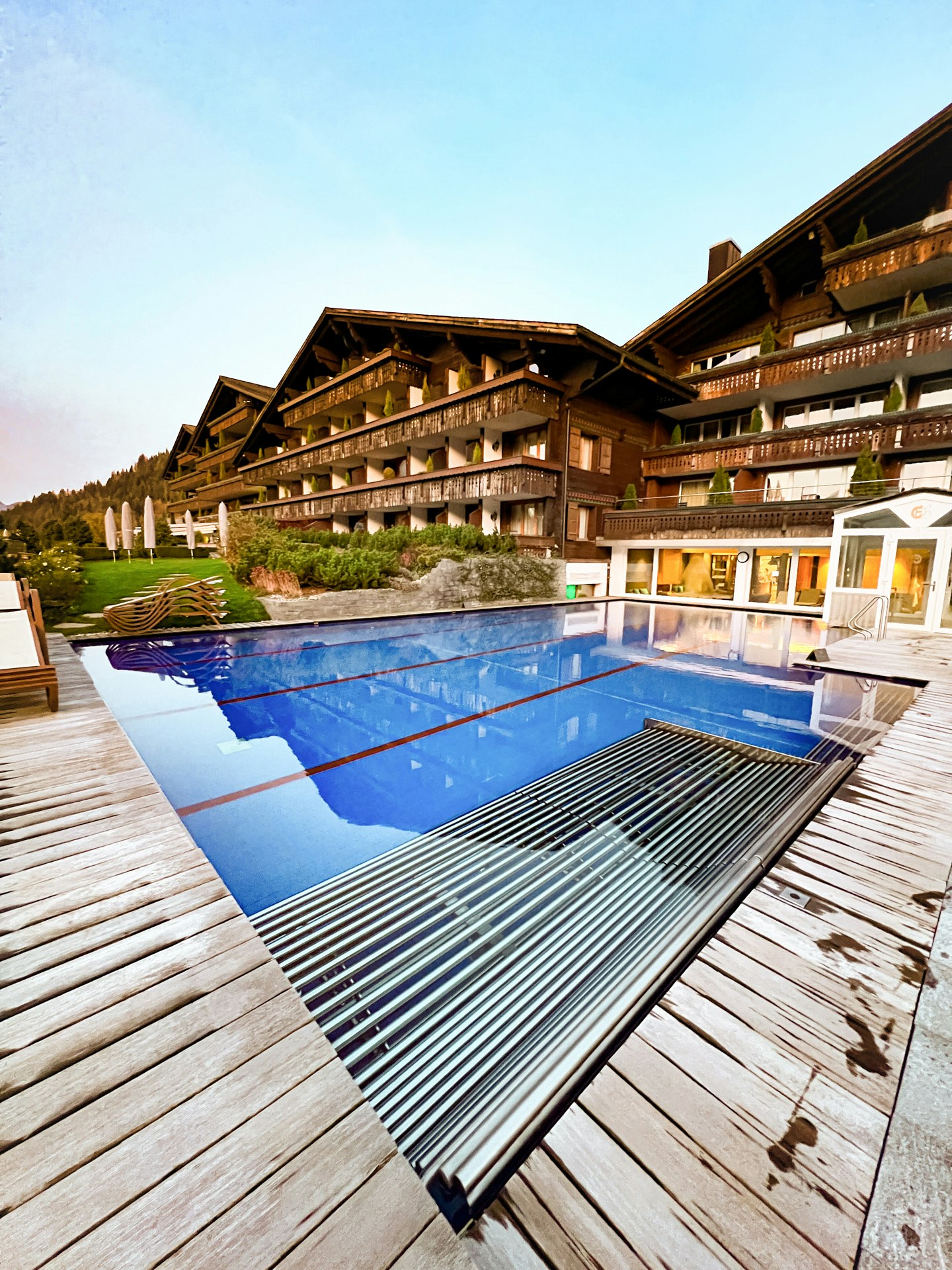 Outdoor sports pool at the Hotel Ermitage Swimming pool with wooden slats all round and a large wooden building complex at the back