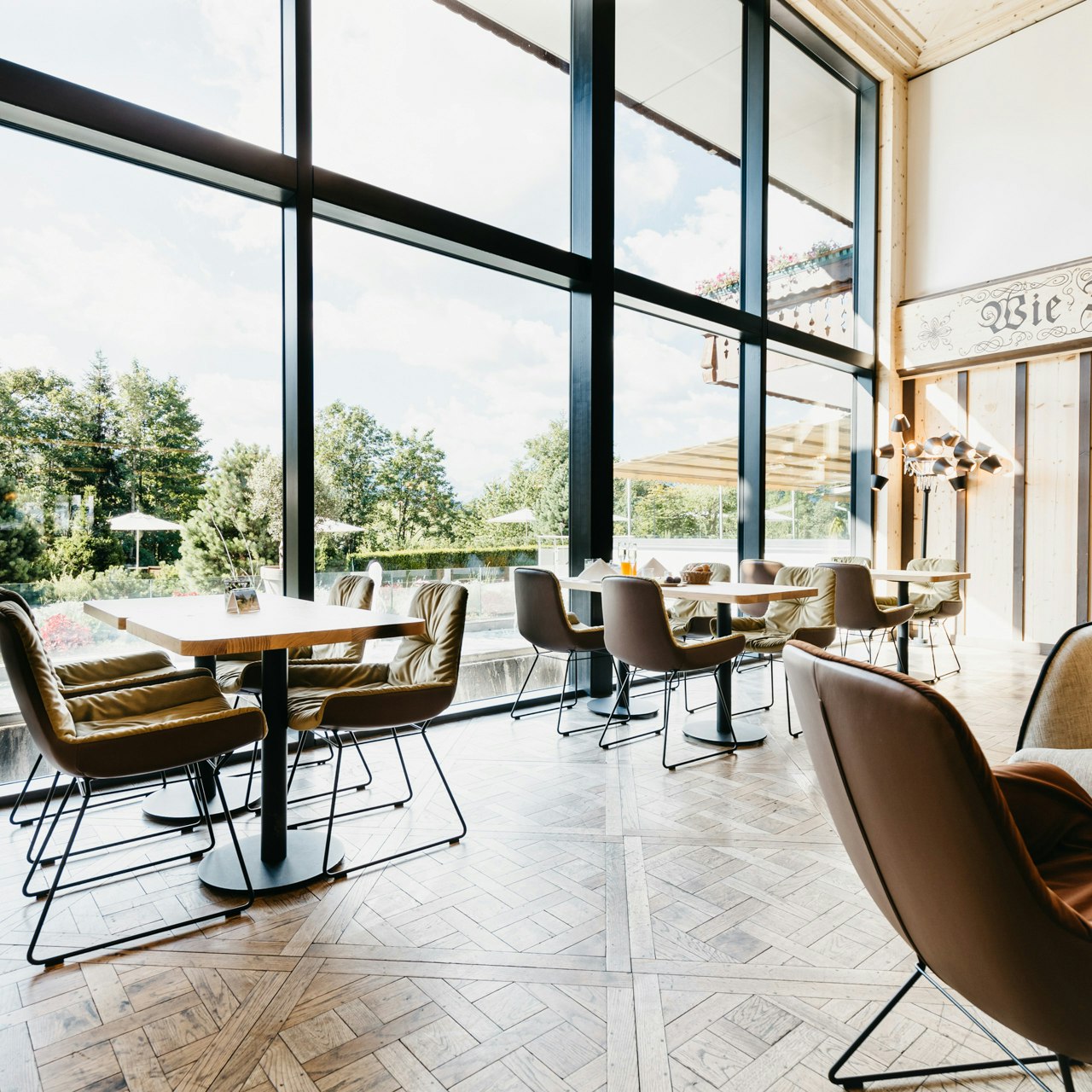 Bärgblick at the Hotel Ermitage Hotel lobby with wooden parquet flooring, upholstered chairs and panoramic windows with a view of the garden
