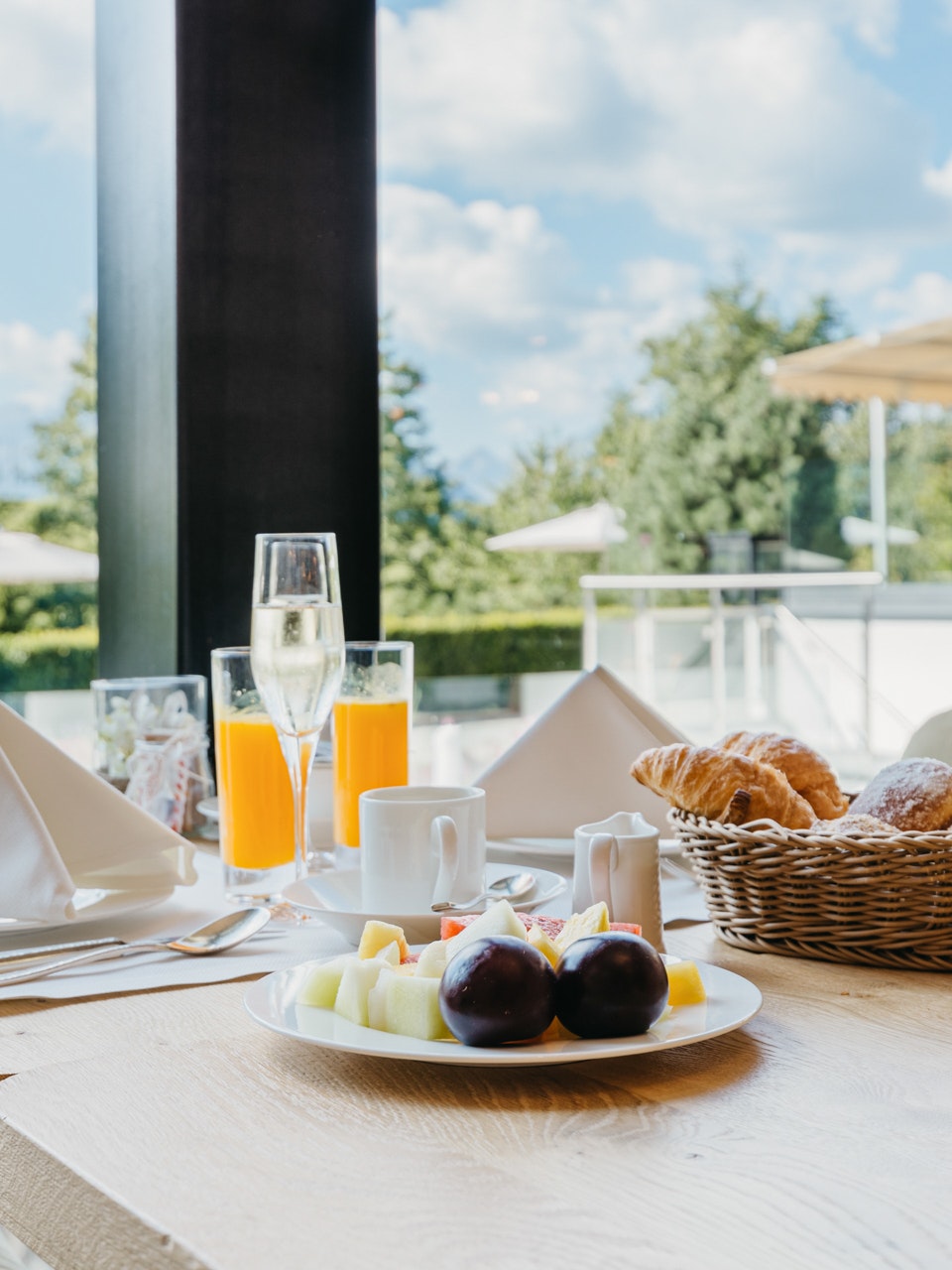 Lobby at the Hotel Ermitage Breakfast with sparkling wine and orange juice on a table, behind a large window with a view of the garden