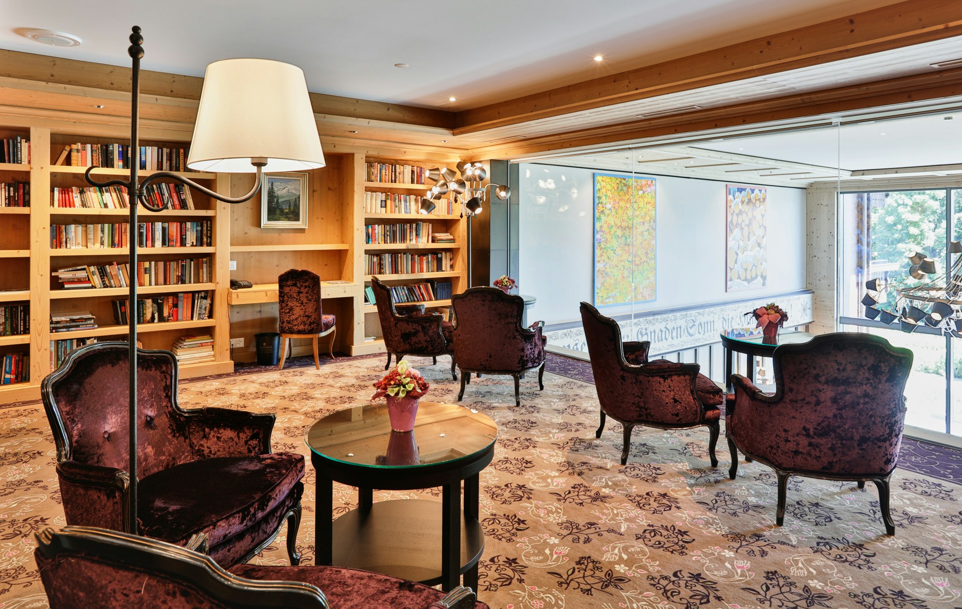 Gemütlich eingerichteter Raum mit Bücherwand und grossem Fenster in die Hotellobby