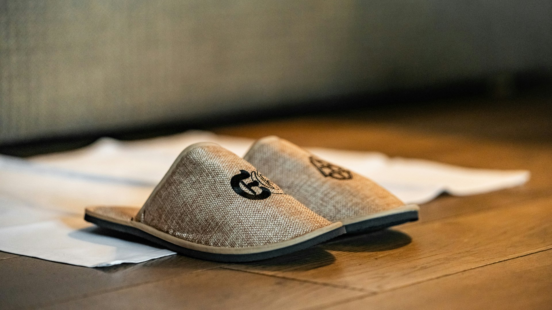 Ermitage bath slippers Bath slippers with logo in front of a bed