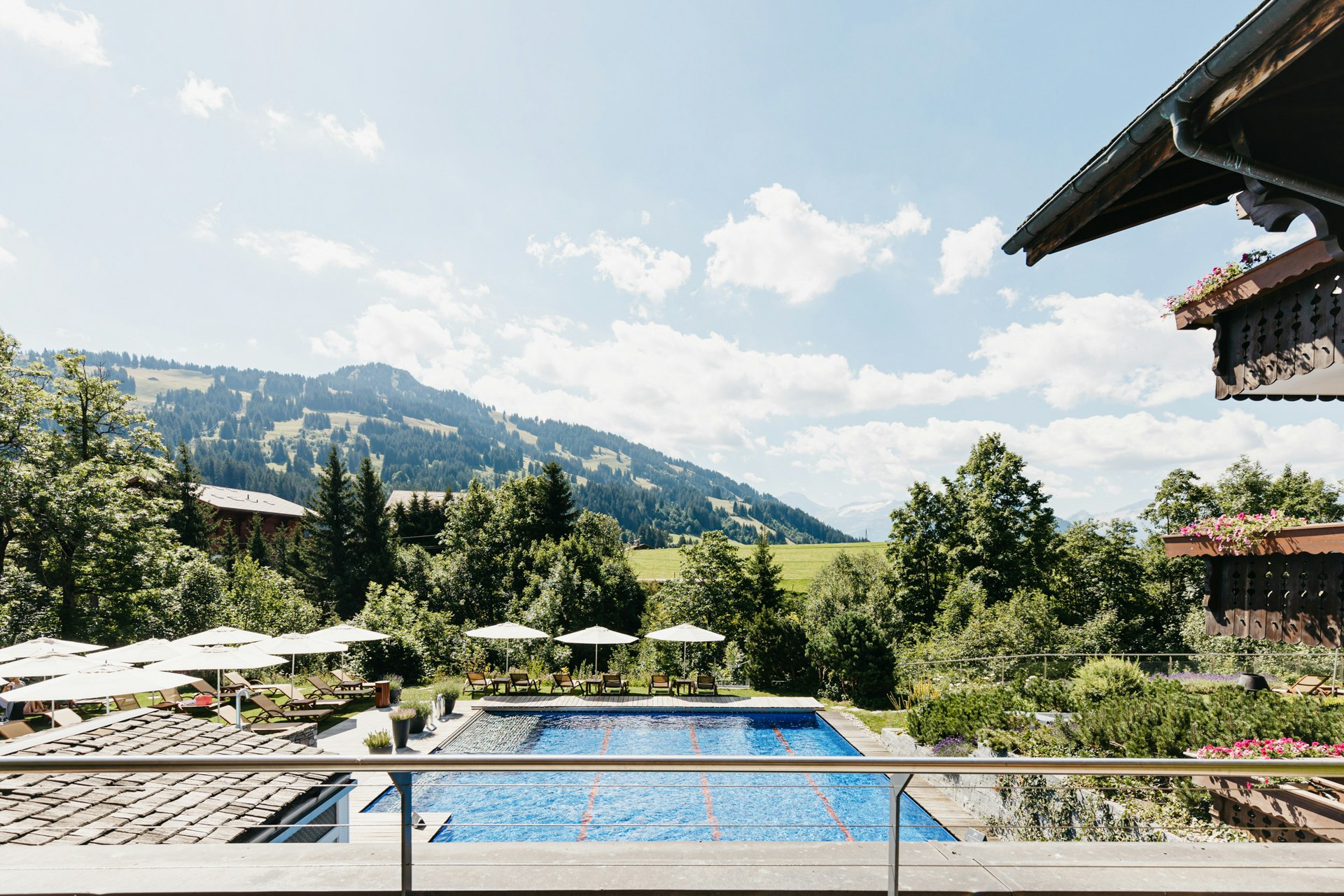 Blick auf ein Swimminpool, Sonnenschirme und Wiesen