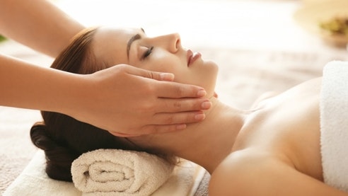 Massage antistress à l'hôtel Ermitage Une femme est allongée sur le dos et reçoit un massage du visage.