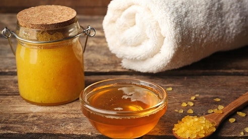 Honig-Peeling im Hotel Ermitage Stillleben mit Honig, Badetuch und Holzlöffel auf Holzunterlage